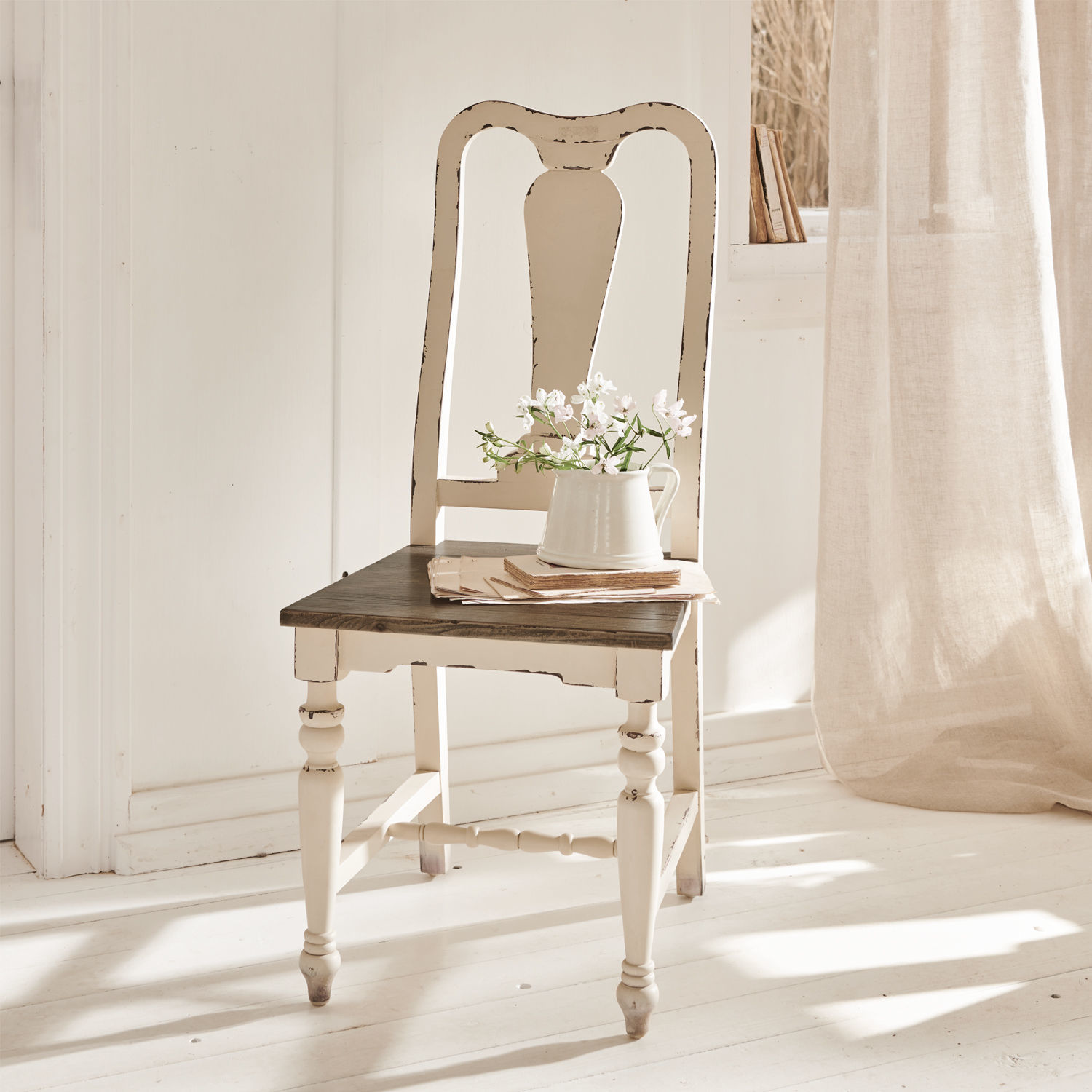 Stoel Harry Witte houten vintage stoel met donkere zitting en vaas met bloemen in lichte kamer