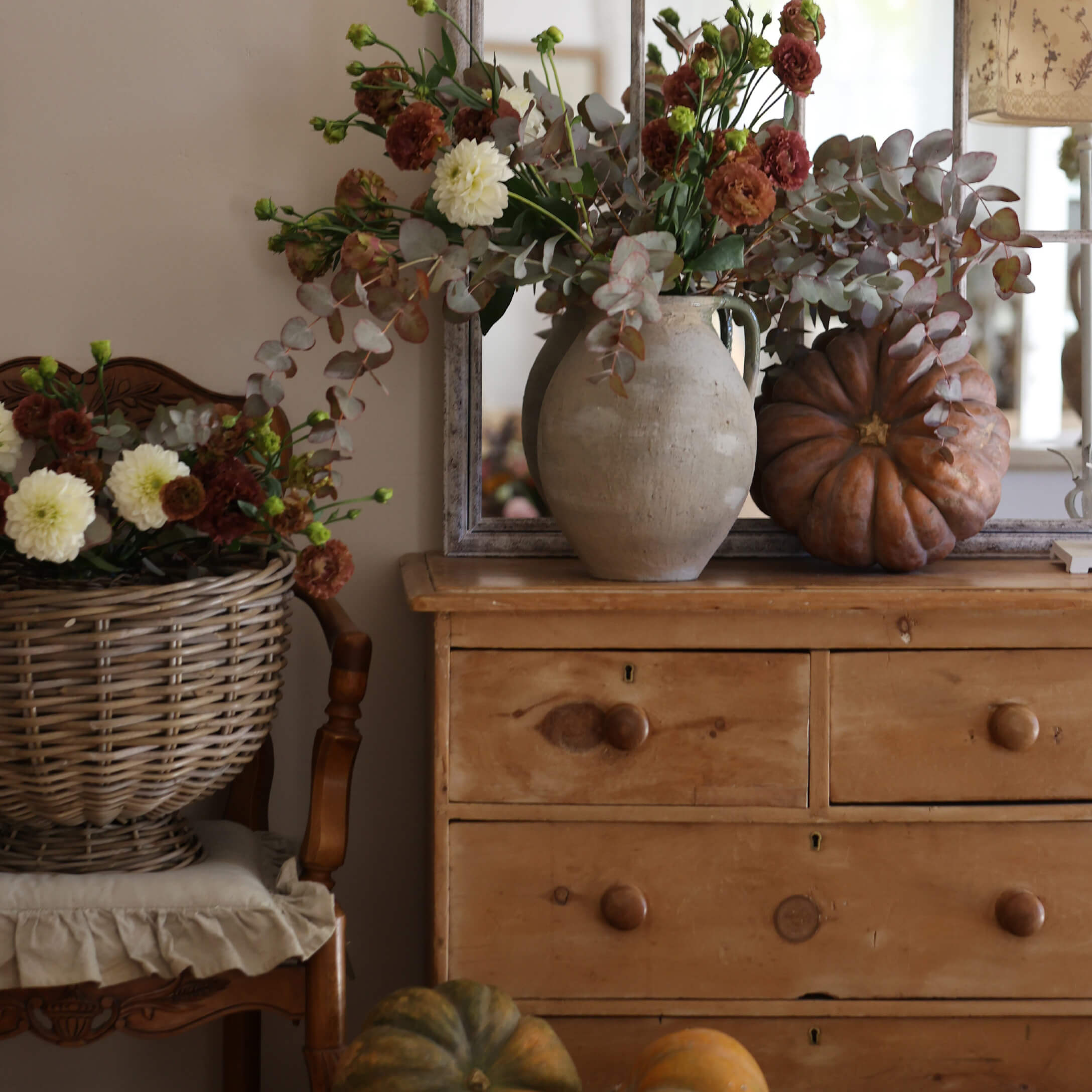 Rustieke houten ladekast met aardewerken vaas, herfstboeket en decoratieve pompoenen in warme setting