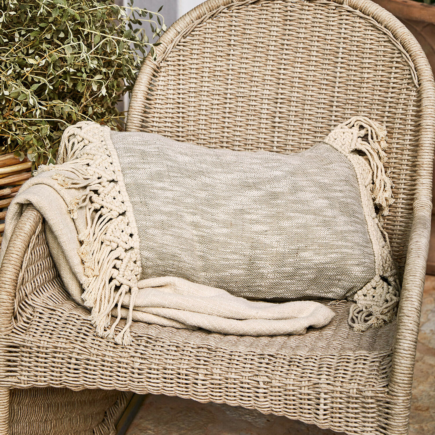 Beige deken met franjes op een rotan stoel, gezellige woondecoratie en textiel
