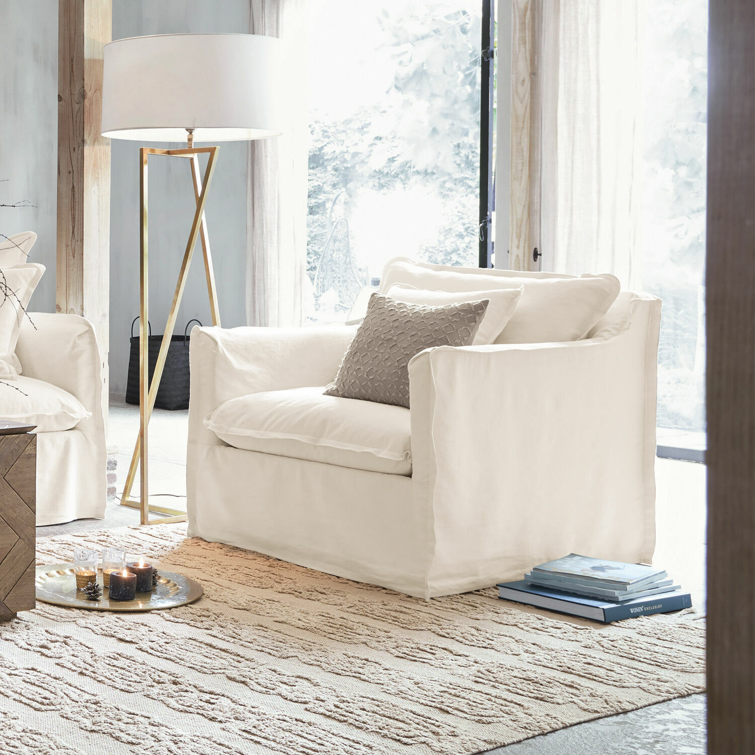 Fauteuil Tienen Witte stoffen fauteuil in lichte woonkamer met vloerlamp en tapijt, modern meubelontwerp.