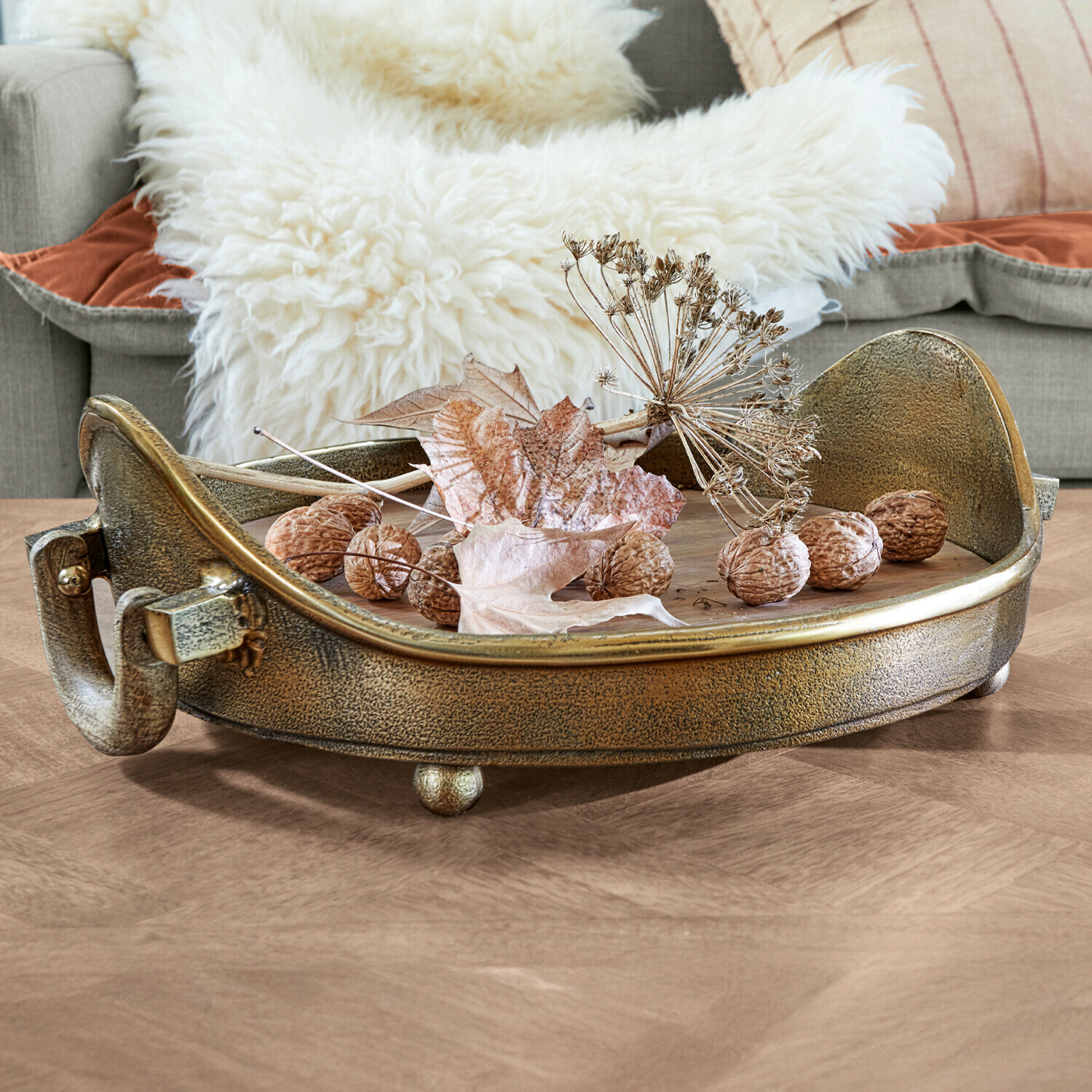 Dienblad Louvil Ronde metalen decoratieve schaal in antiek gouden kleur met walnoten en droge bladeren op houten tafel