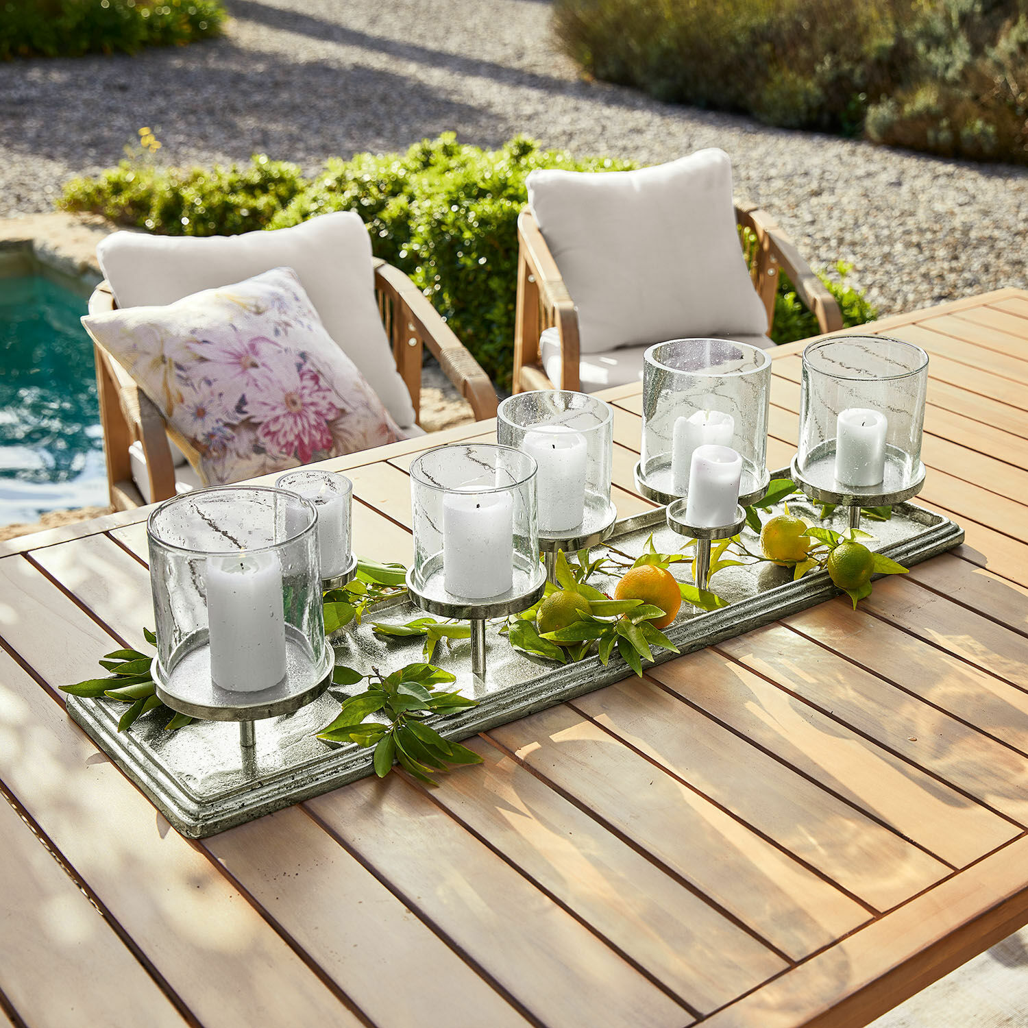 Decoratieve kandelaar van glas en metaal met witte kaarsen op houten tafel in tuin