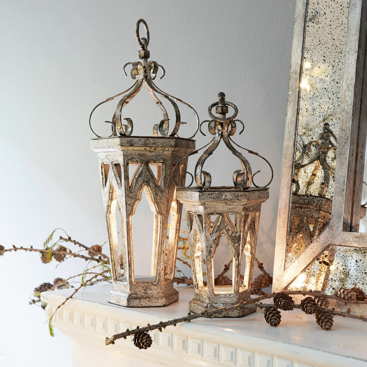 Siervoorwerp set van 2 Morvant Decoratieve metalen lantaarns in vintage stijl in antiek zilver op schoorsteenmantel met dennenappels