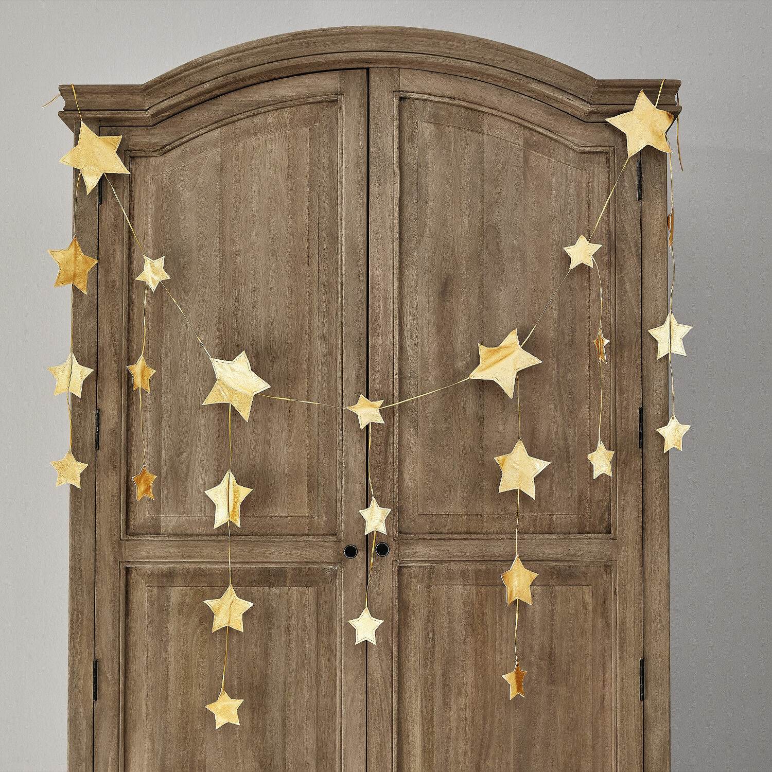 Guirlande Étoilin Gouden sterren slinger aan houten kast, feestelijke woondecoratie voor kerst