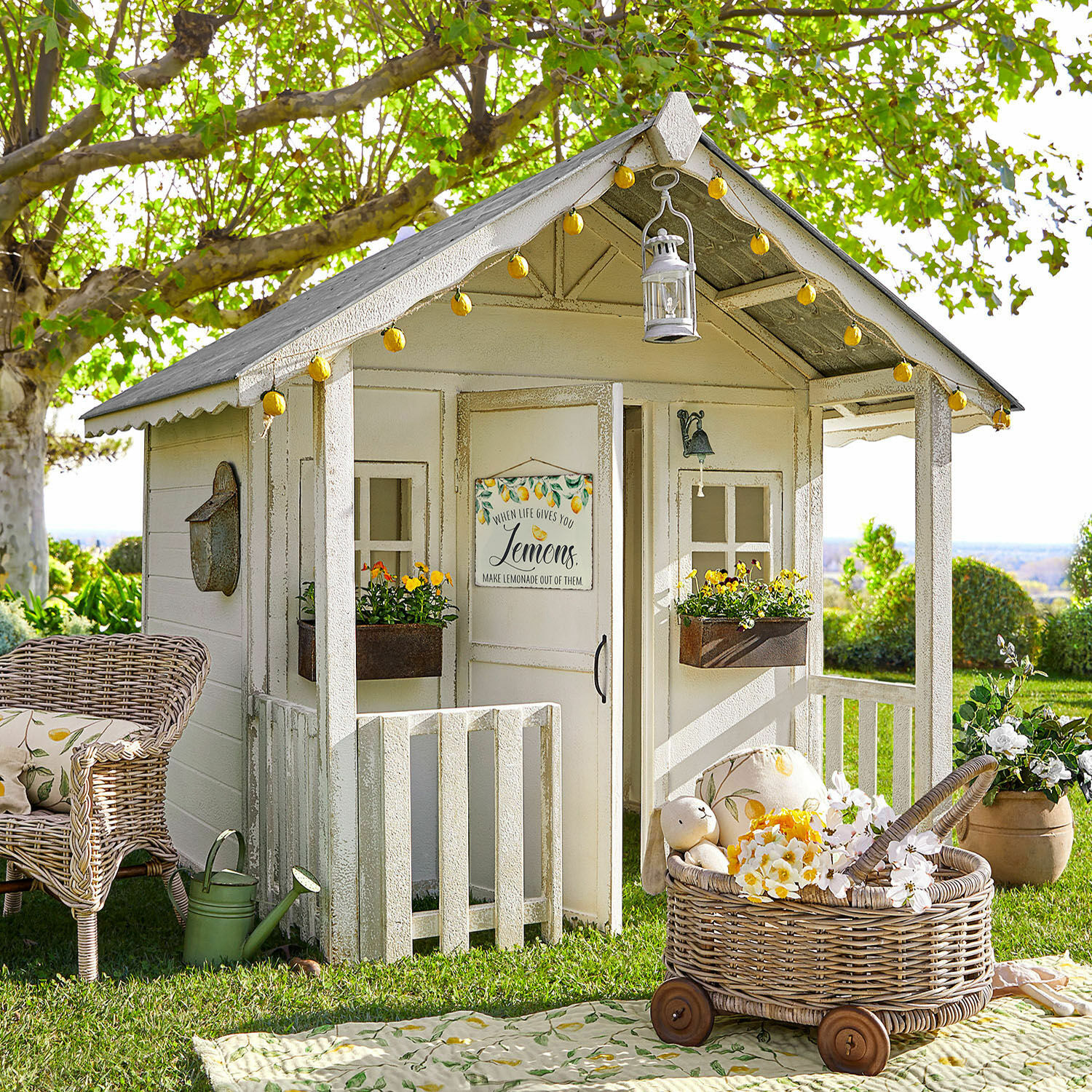 Maisonnette de jardin pour enfant Pouponnet Maisonnette de jardin en bois blanc avec décorations citron et panier en osier à roulettes sur l'herbe