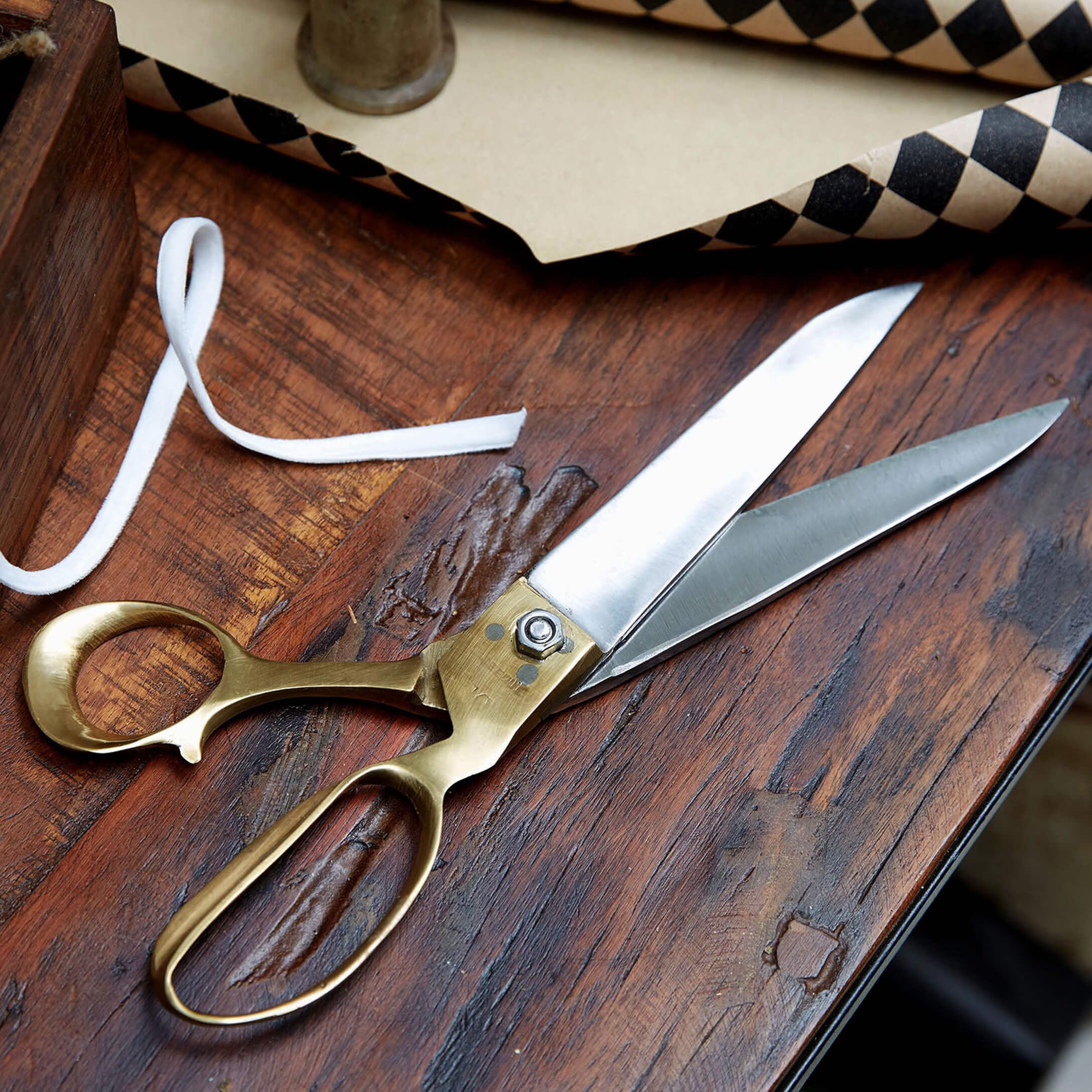 Naaischaar van roestvrij staal en messing op houten tafel voor stoffen en naaien