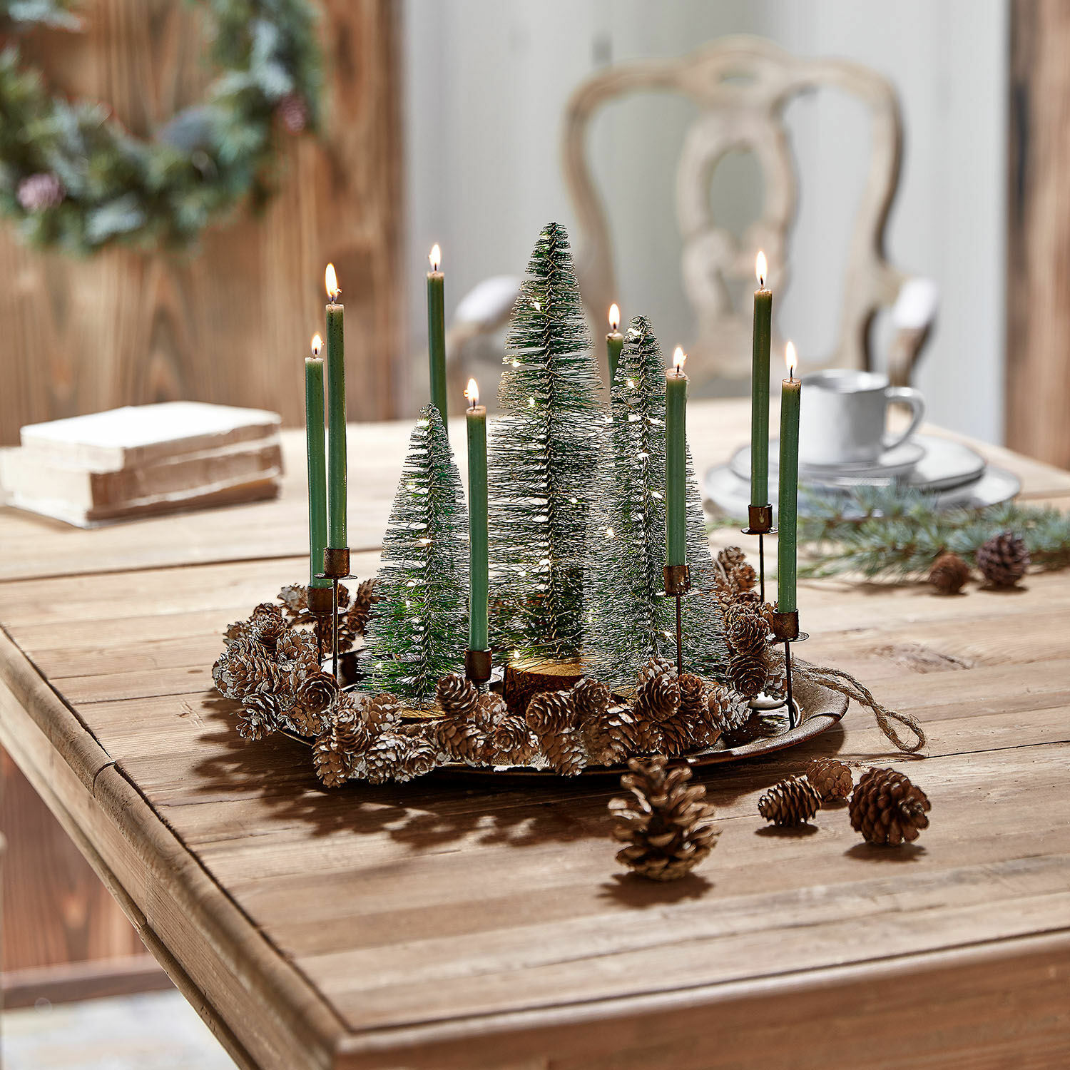 Decoratieve kerstkrans met groene kaarsen en dennenappels op houten tafel