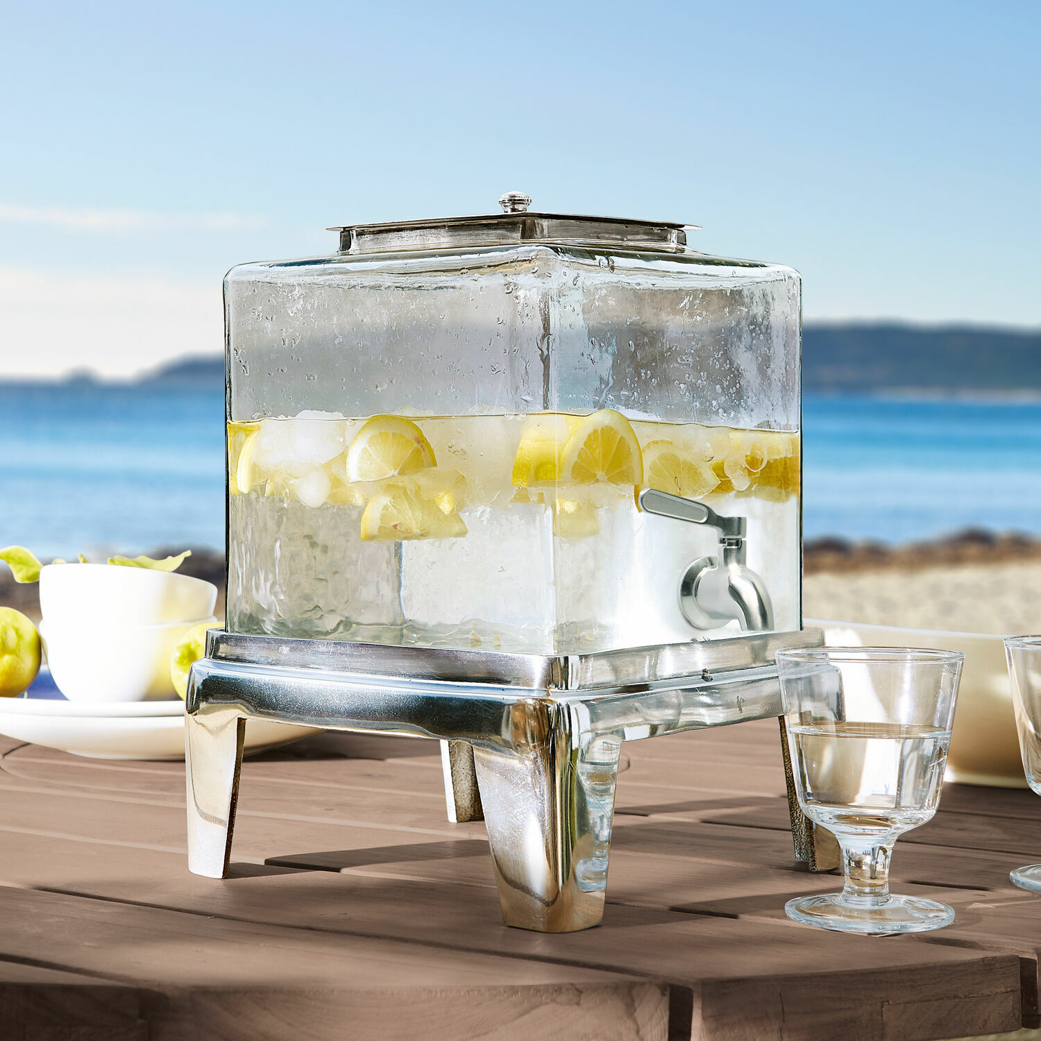 Drankdispenser Osric Glazen drankendispenser met metalen voet en kraan, gevuld met water, citroen en ijsblokjes