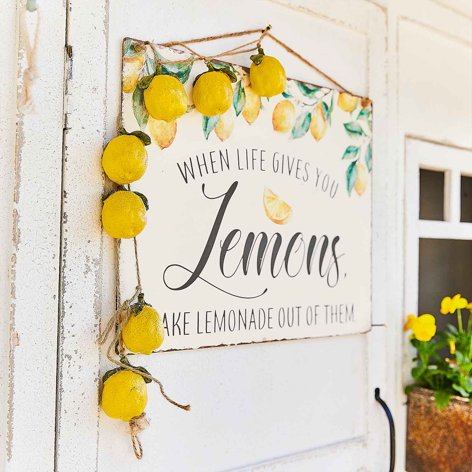 Decoratief bord met citroenen en gele citrusslinger aan een witte deur