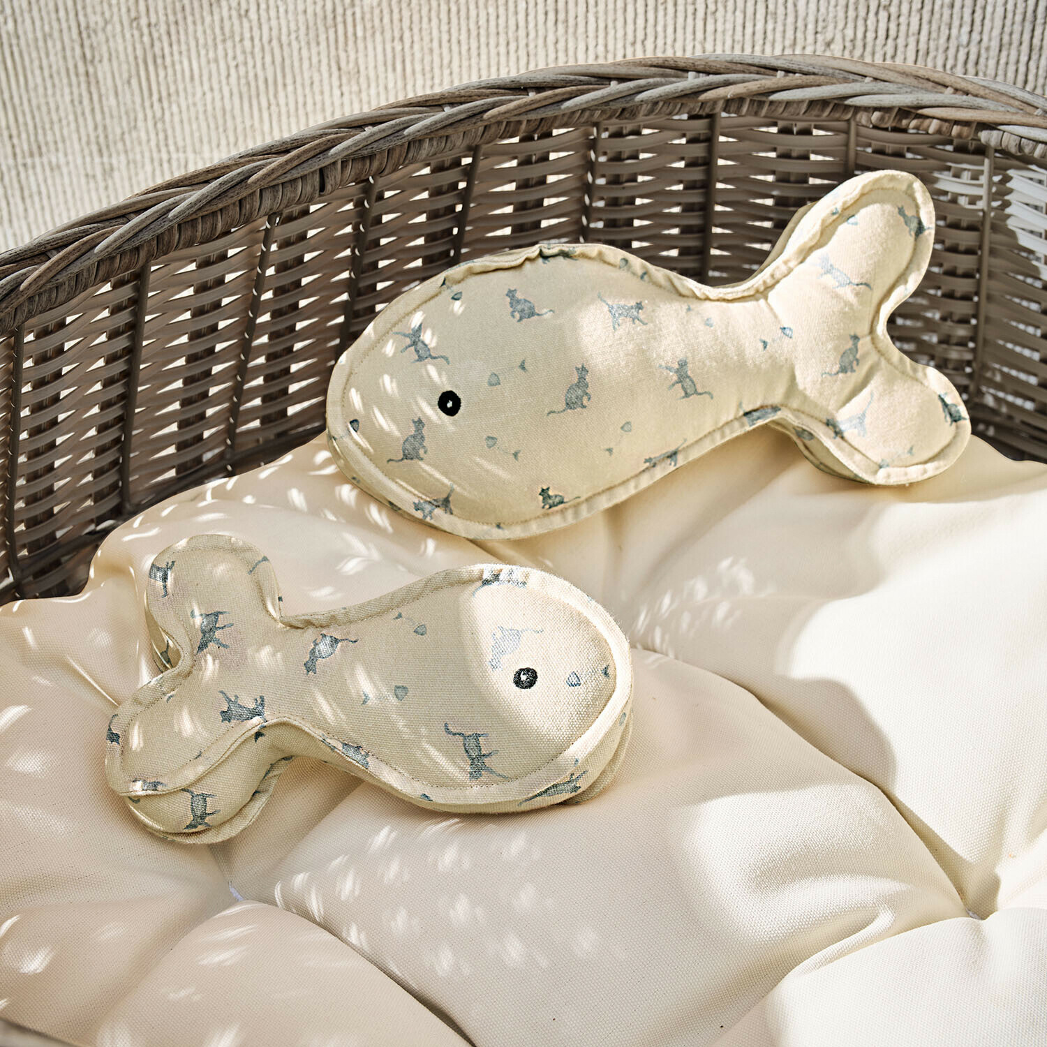 Kussen set van 2 Oceravia Beige visvormige kussens met kattenprint op een rotan stoel met licht kussen