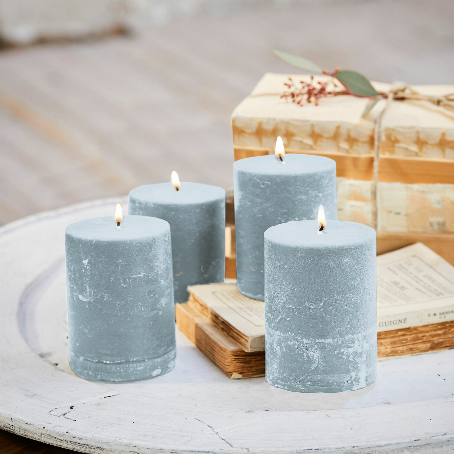 Set van vier blauwe waskaarsen op witte houten tafel met boeken en cadeau