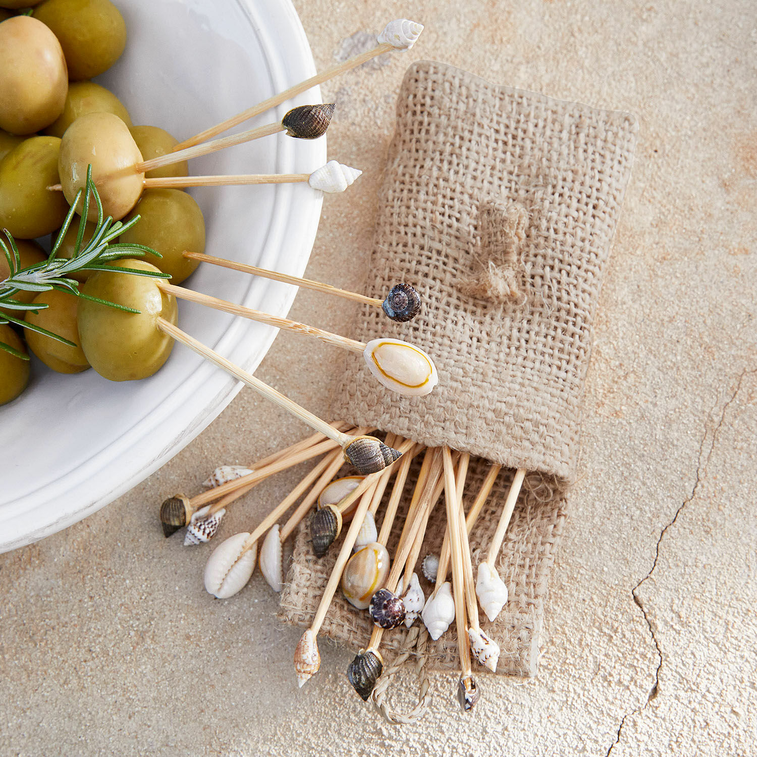 Ensemble de cure-dents avec coquillages naturels dans une pochette en lin près d'olives vertes