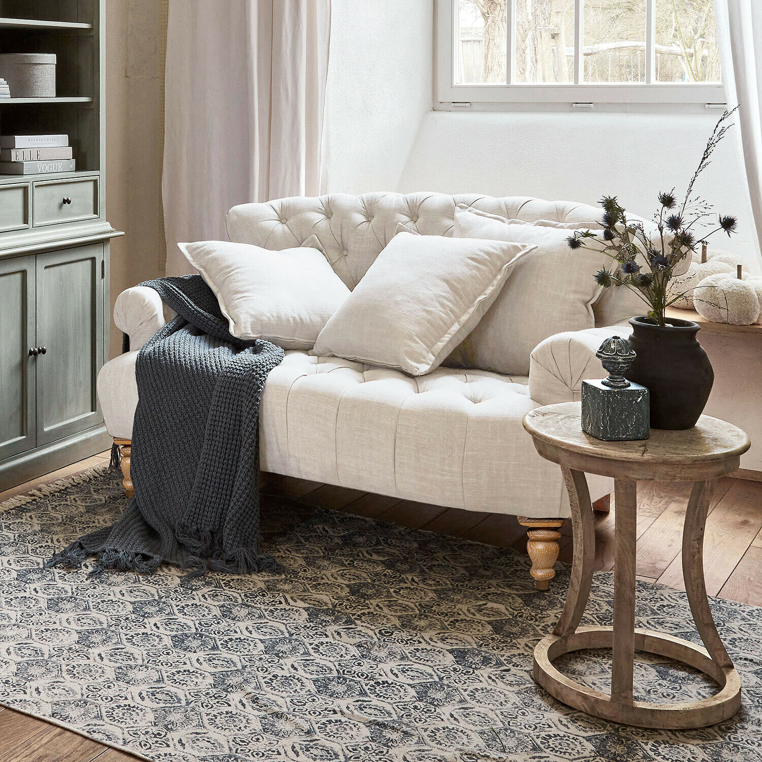 Bank Springfield Village Beige gestoffeerde linnen bank met kussens en grijze gebreide deken in gezellige woonkamer met houten tafel