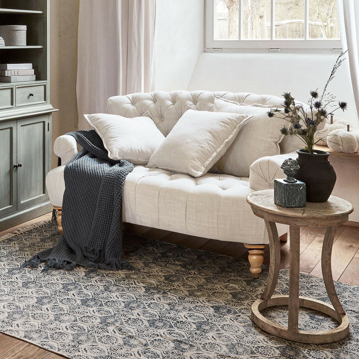 Bank Springfield Village Beige gestoffeerde linnen bank met kussens en grijze gebreide deken in gezellige woonkamer met houten tafel