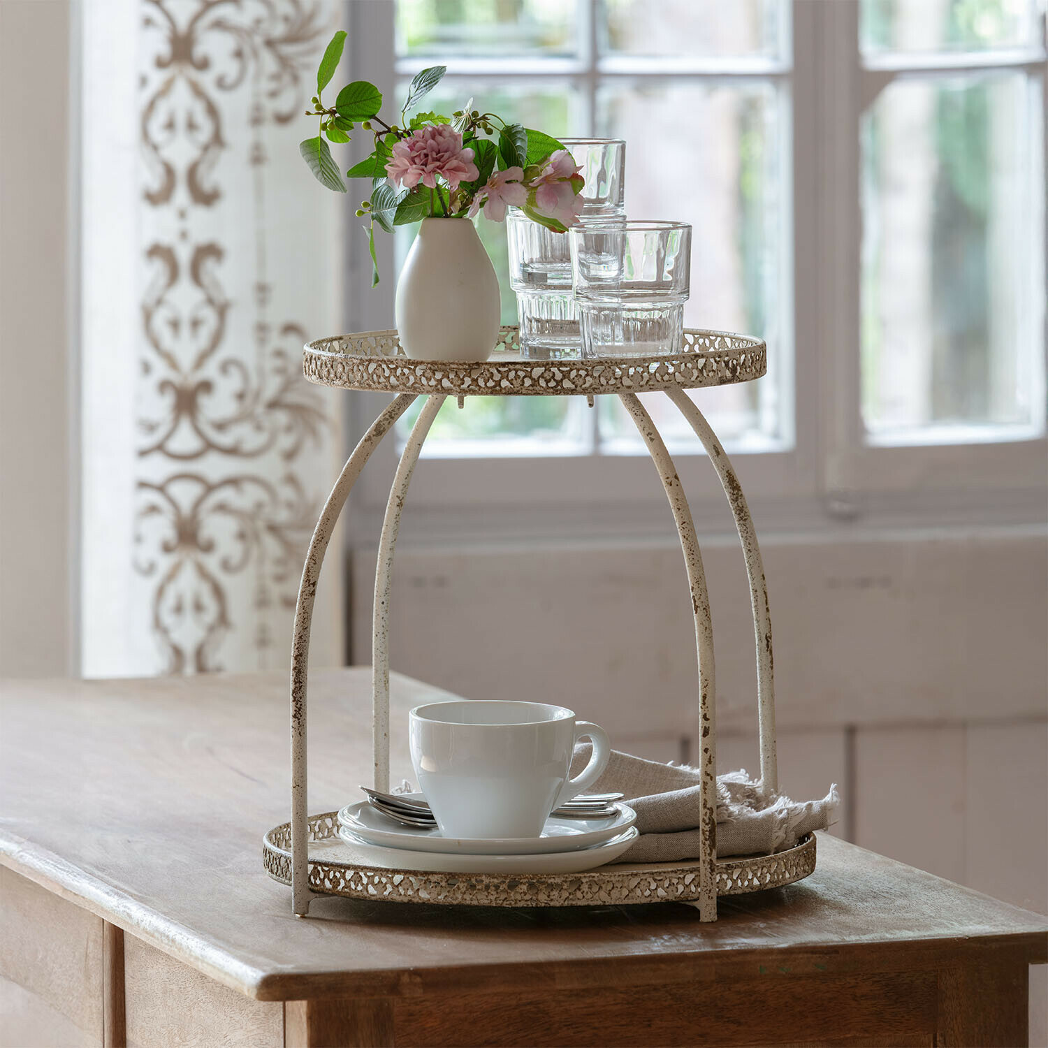Etagère Nolienne Tweeledig metalen vintage stijl rek in crèmekleur met kopje en glazen op houten tafel