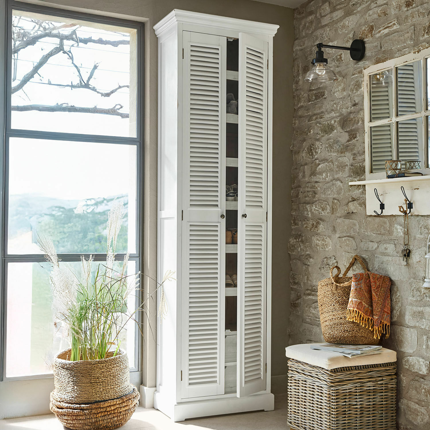 Meuble à chaussures Blossomby Armoire blanche en bois avec portes à persiennes dans un intérieur rustique avec mur en pierre