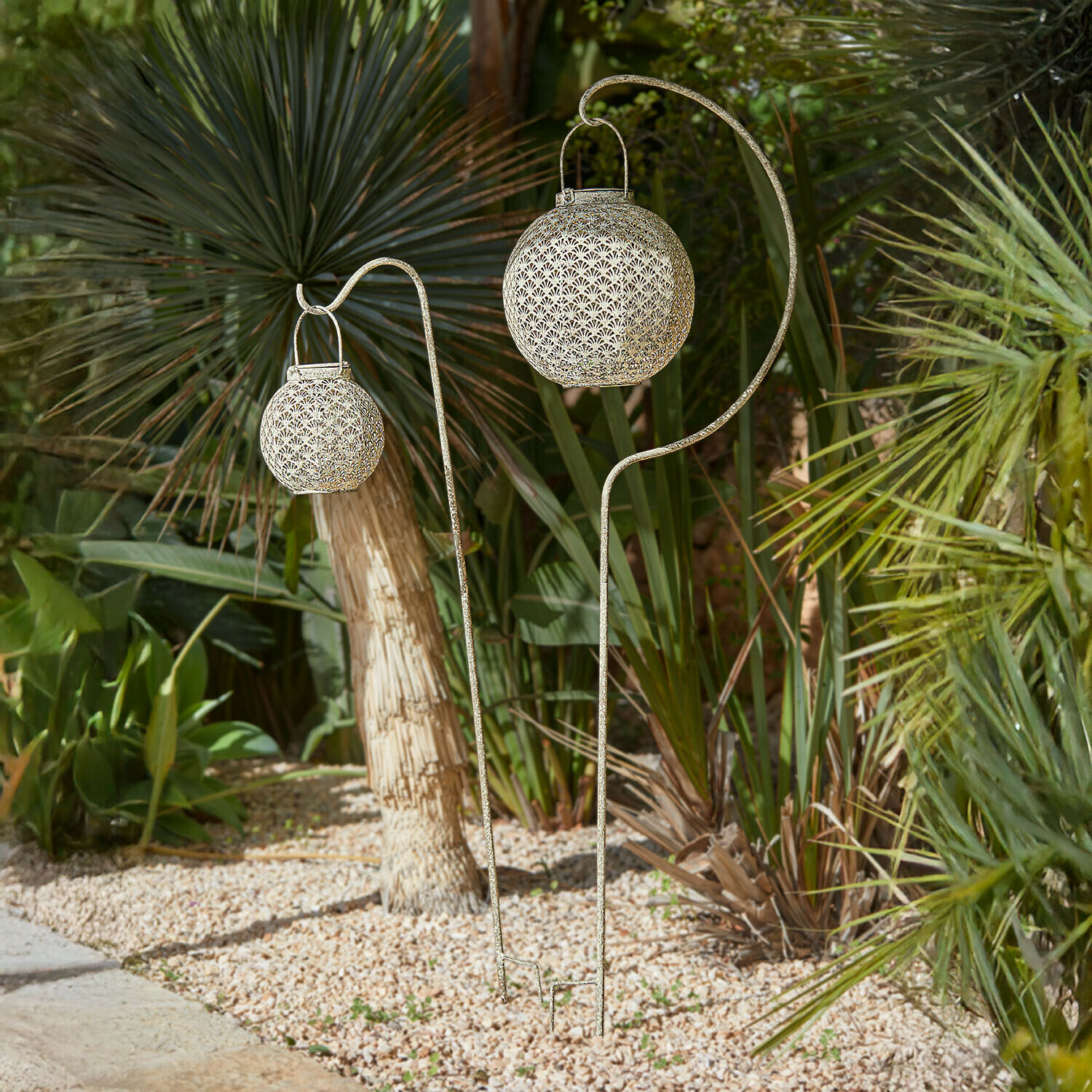 Tuinsteker set van 2 Omirah Decoratieve metalen tuinlantaarns in antiek goud op standaards tussen groen planten