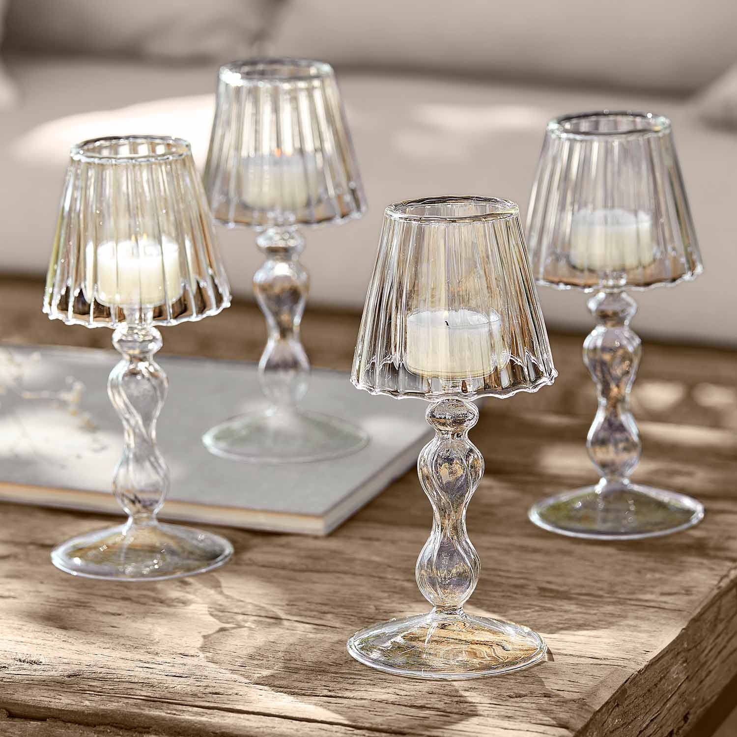 Bougeoirs en verre transparent avec bougies blanches sur table en bois pour décoration intérieure