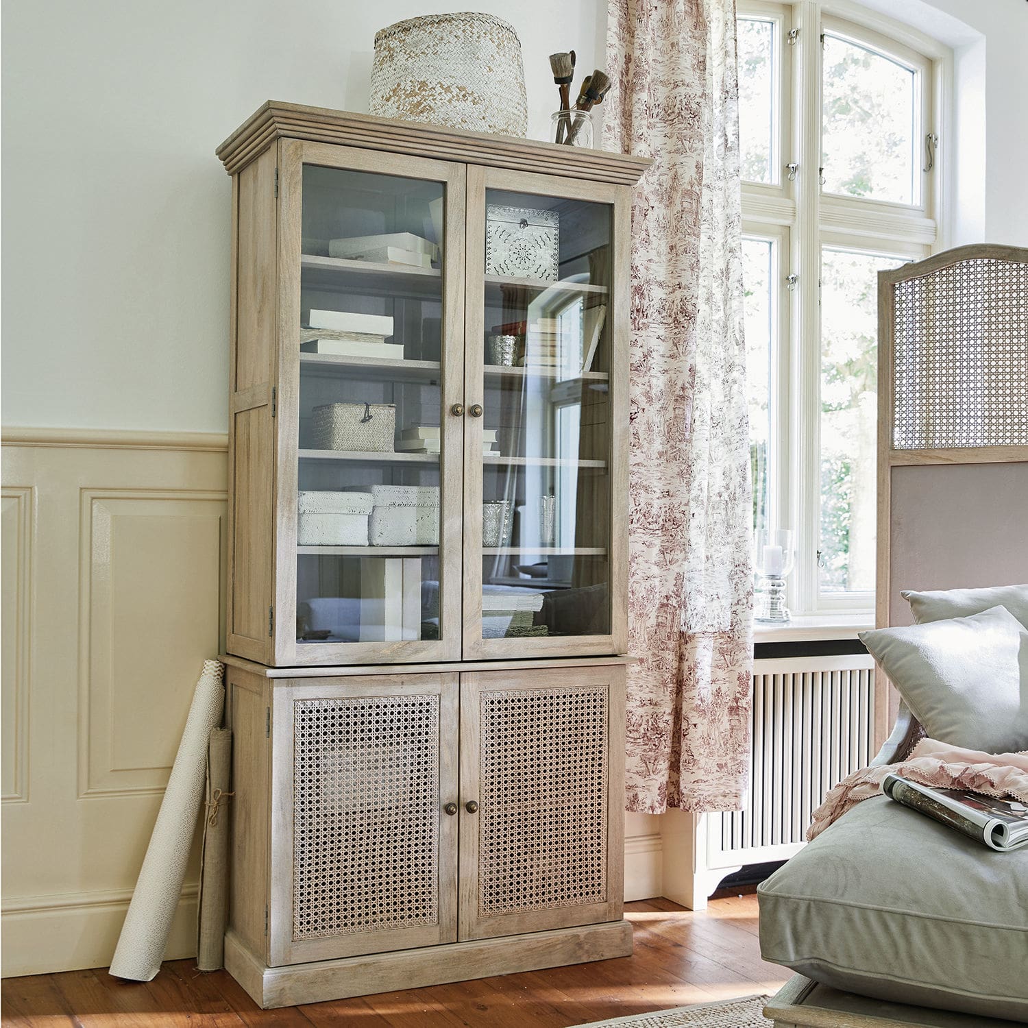 Armoire Dronne Vitrine en bois clair avec portes vitrées et en osier pour un salon lumineux et élégant