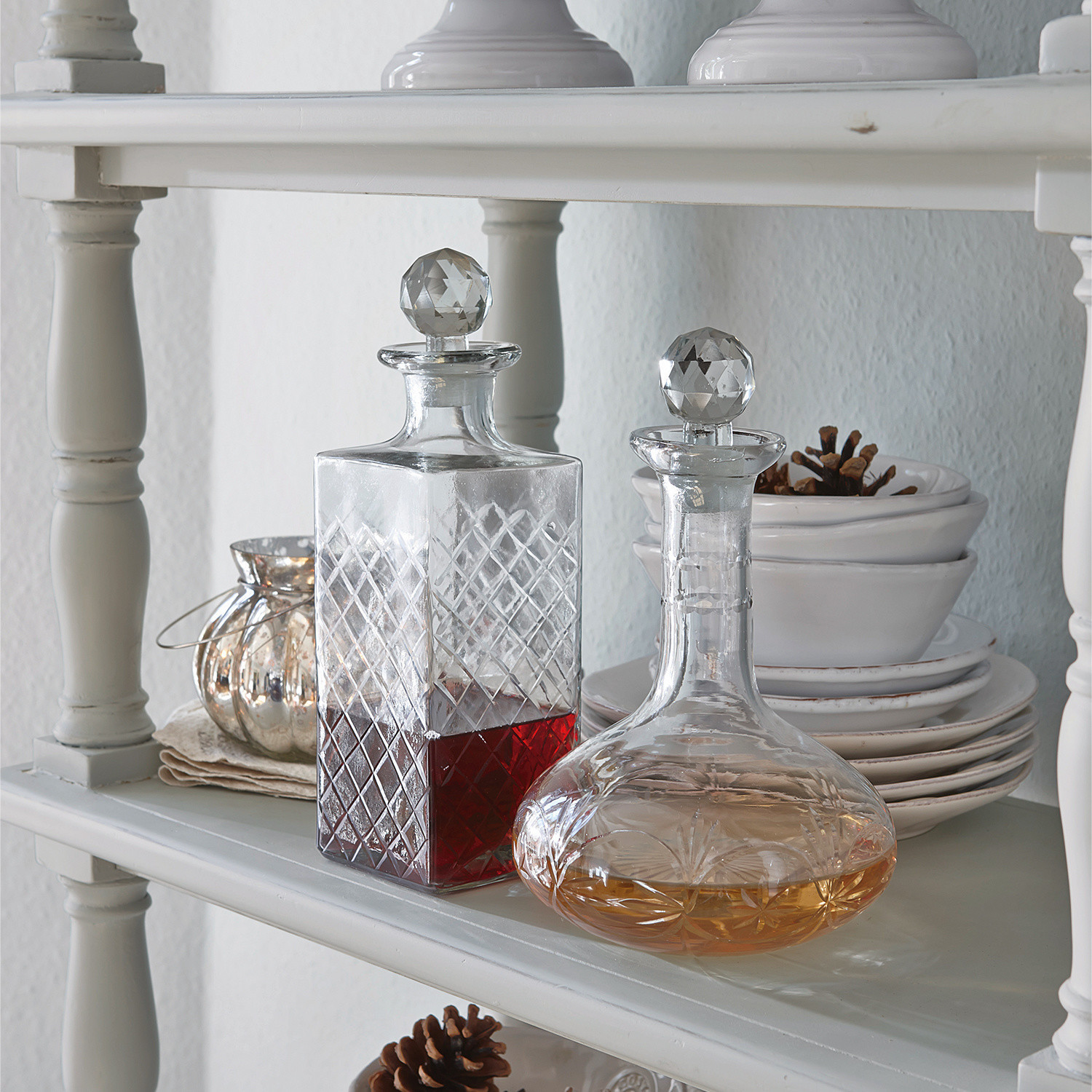Carafes en verre avec bouchons en cristal sur étagère blanche avec boissons rouge et ambrée