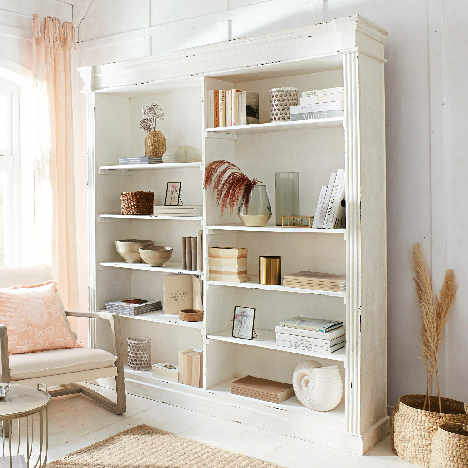 Étagère Barrow Creek Étagère en bois blanc avec décorations et livres dans un salon lumineux et chaleureux aux accents naturels