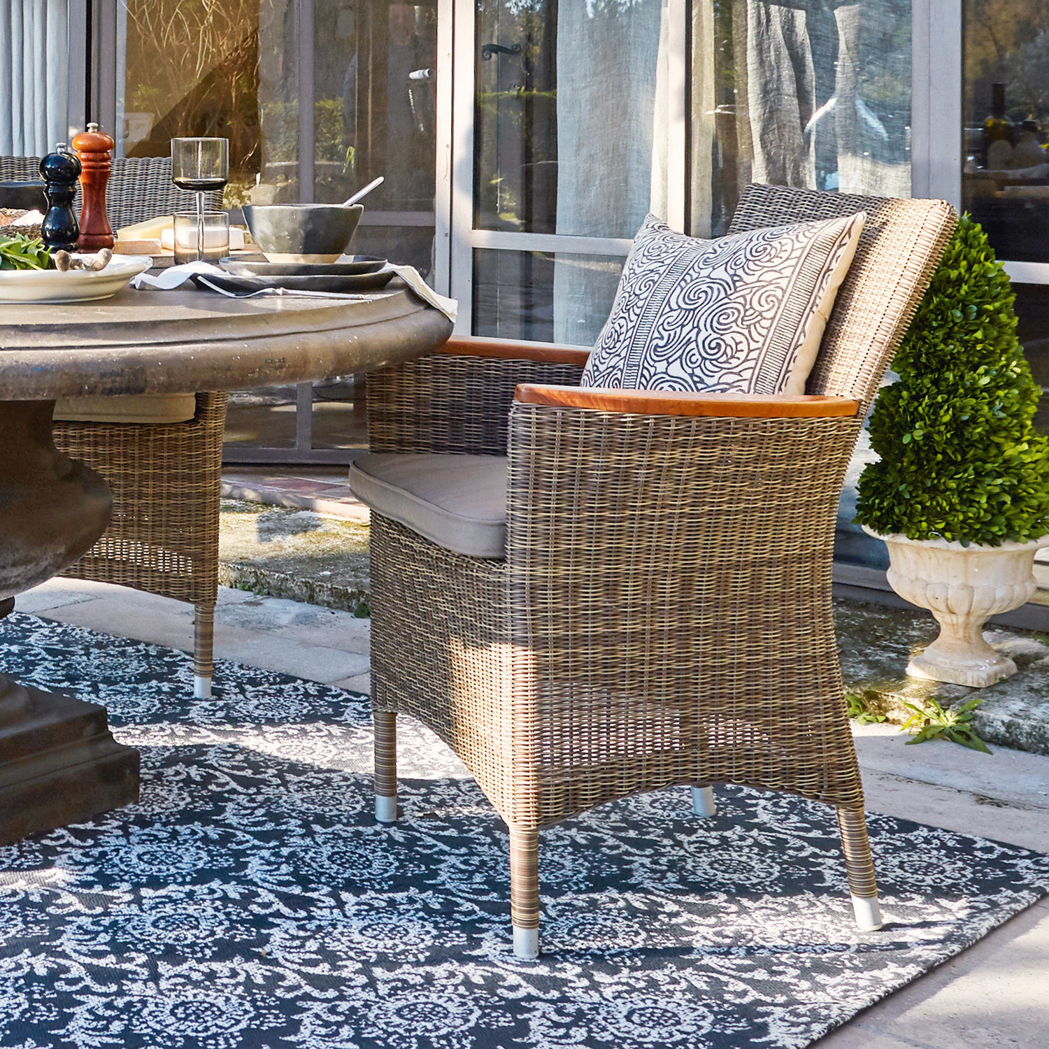 Fauteuil Casper Rotan stoel in natuurlijke kleur met kussen en houten armleuningen op terras