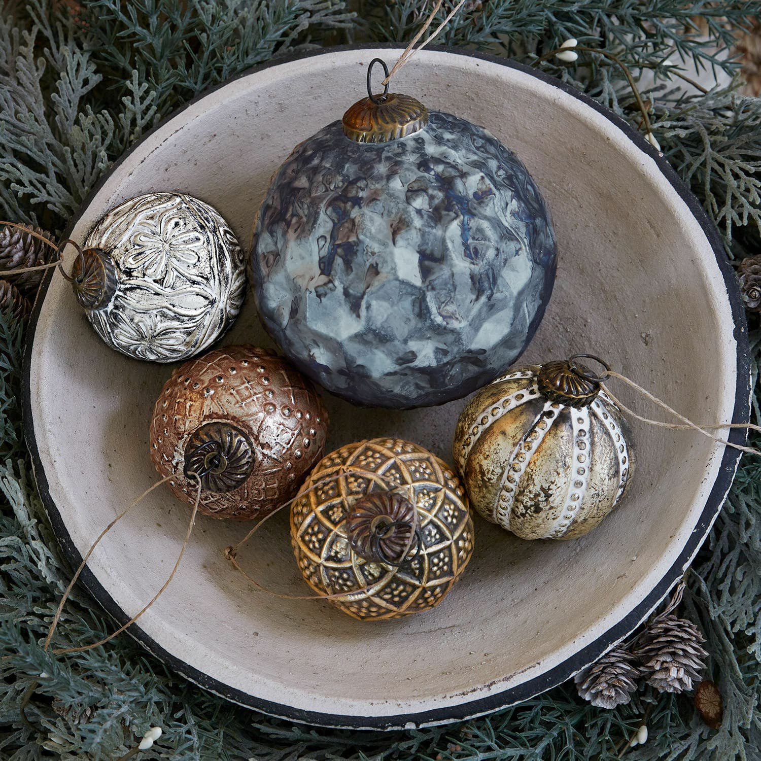 Lot de 5 décorations de Noël Jilian Boules de Noël décoratives en métal multicolores dans un bol en céramique sur fond vert