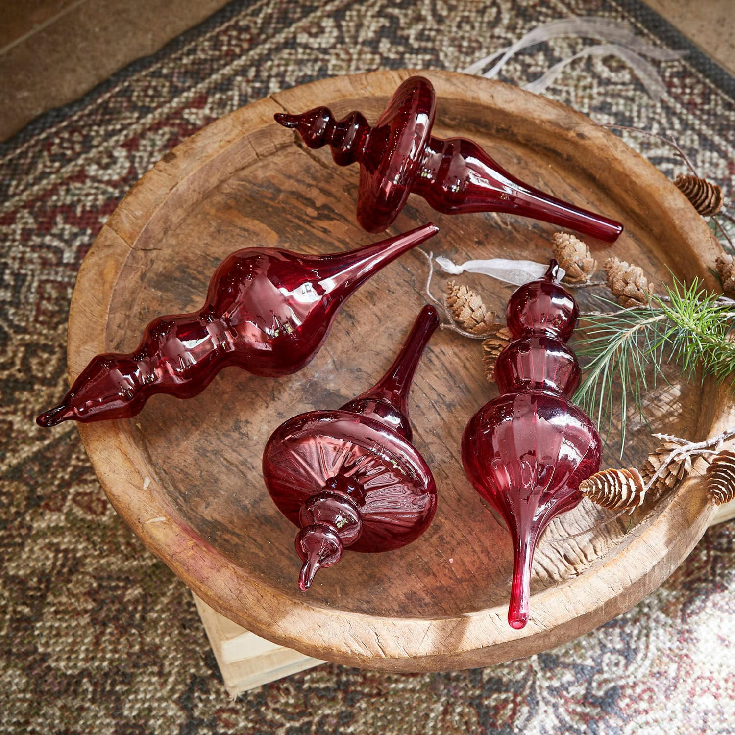 Hanger set van 4 Camorita Vier rode glazen kerstversieringen op een houten schaal met dennenappels en een takje