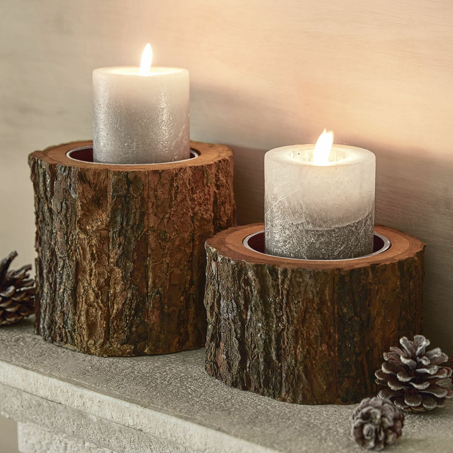 Twee grijze kaarsen op natuurlijke houten kandelaren met schors, rustieke interieurdecoratie