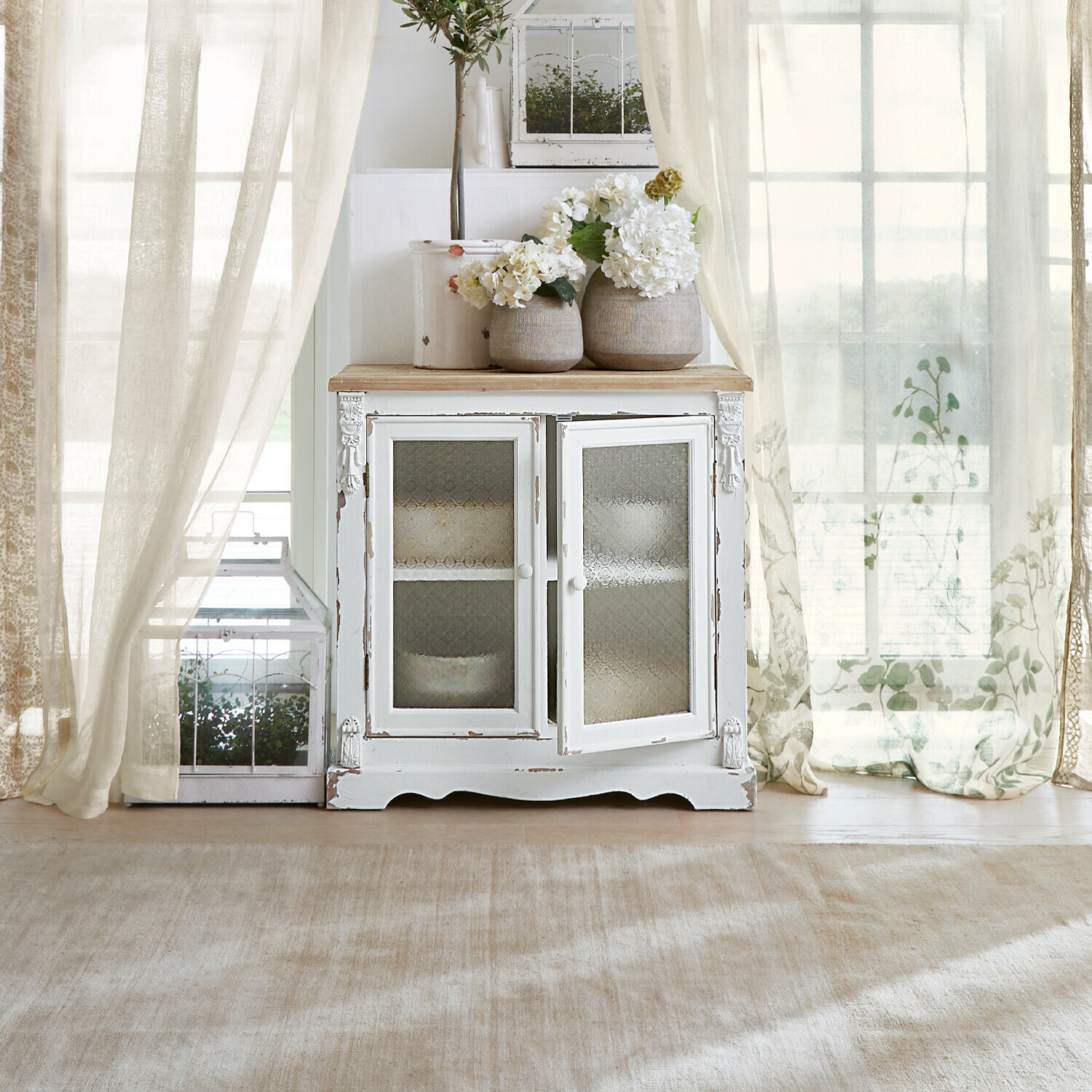 Commode South Yarmouth Buffet en bois blanc avec portes vitrées et vases décoratifs fleuris dans un intérieur lumineux