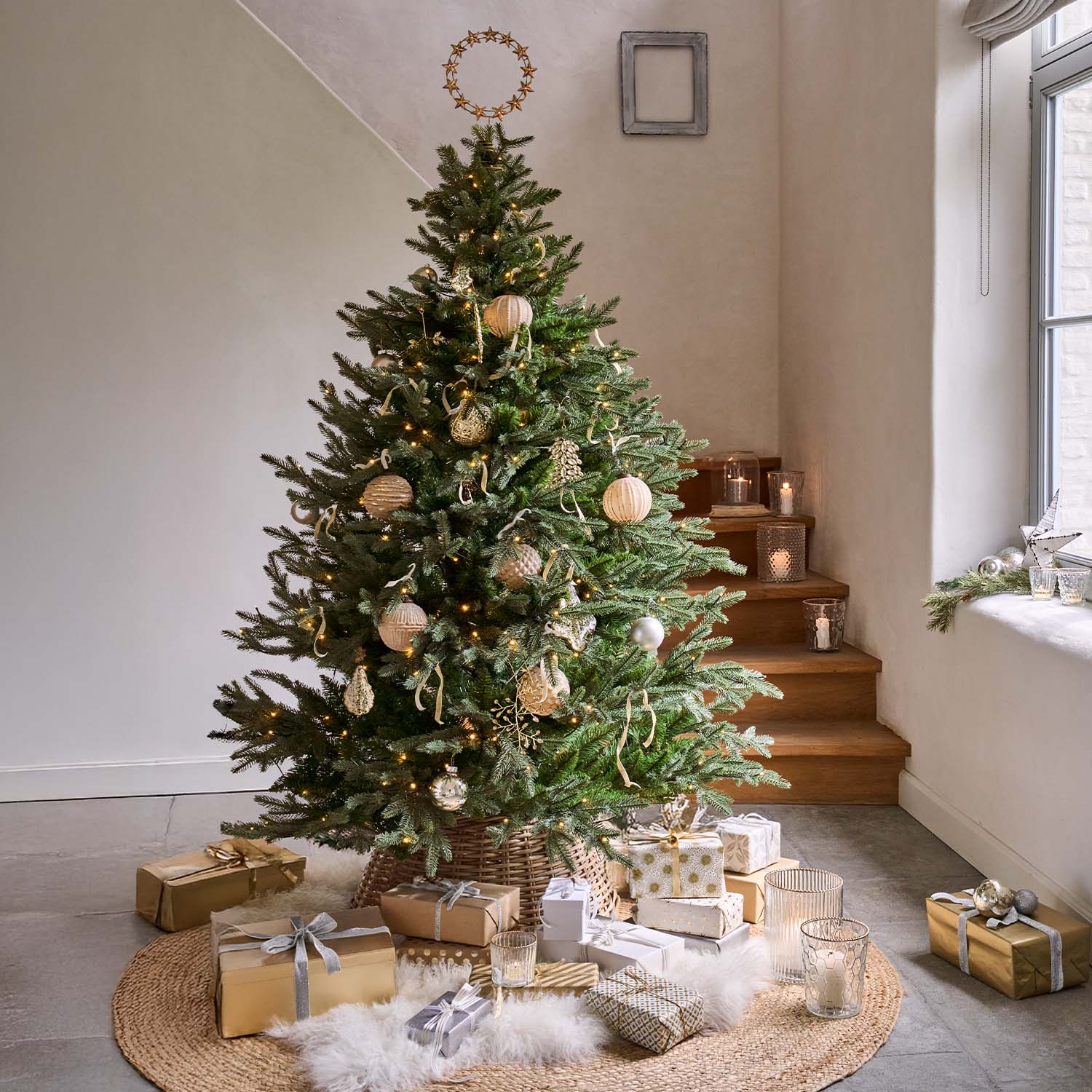 Sapin vert décoré d'ornements naturels et cadeaux dorés sur un tapis rond dans une pièce lumineuse