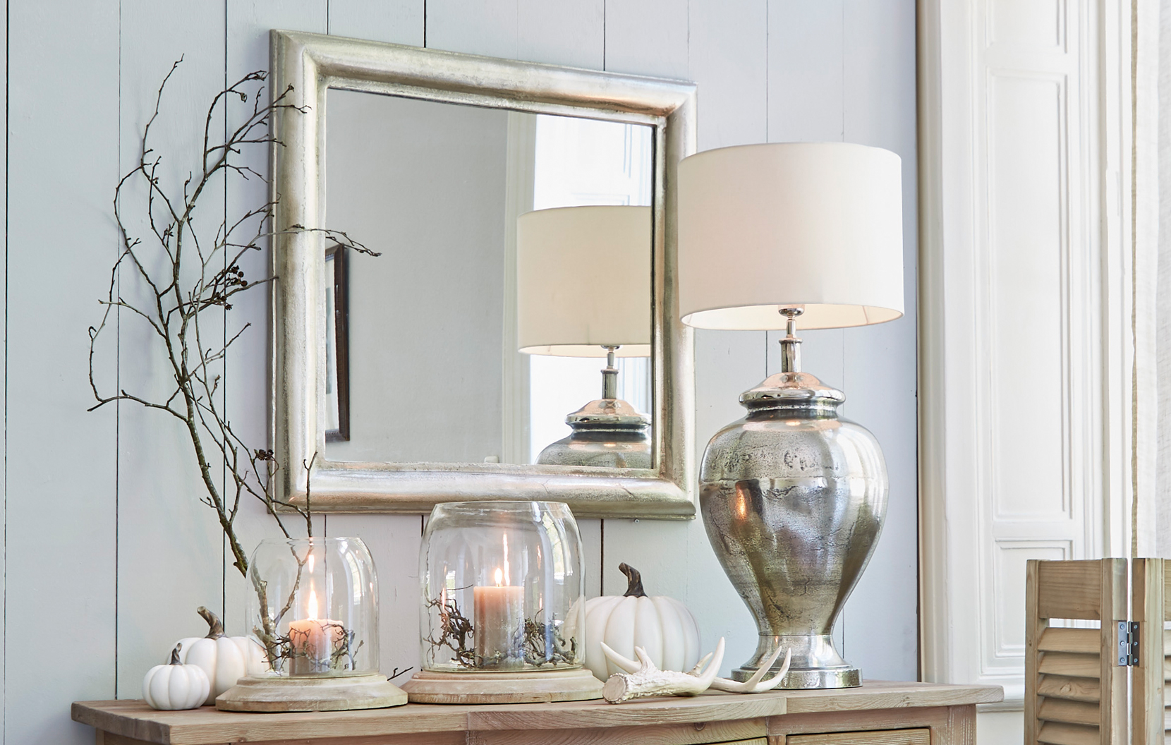 Intérieur classique élégant avec miroir argenté, lampe en métal et décorations sur meuble en bois
