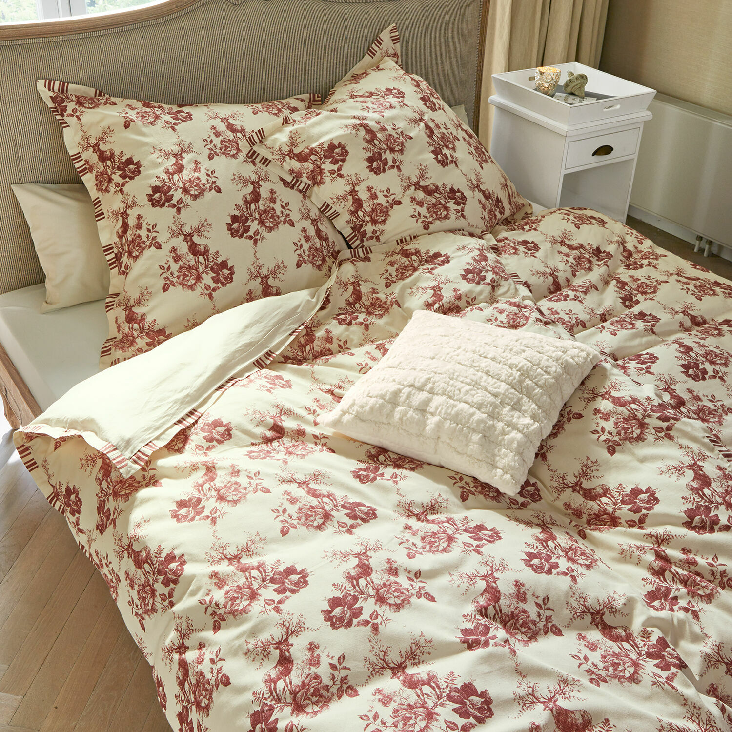 Dekbedovertrekset Renique Katoenen beddengoed in crème met rood hert- en bloemenpatroon, decoratief kussen op bed