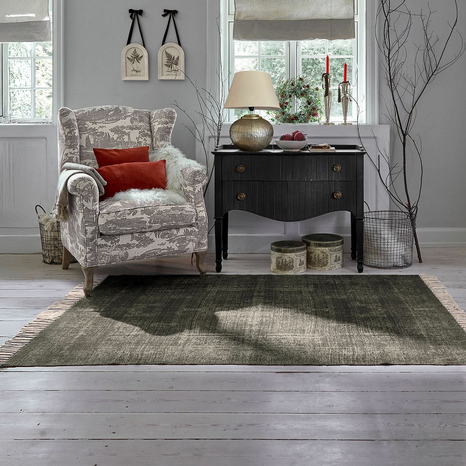 Vloerkleed voor binnen en buiten Belaric Gezellige beige-grijs patroon fauteuil met rode kussens naast zwarte vintage ladekast in lichte woonkamer