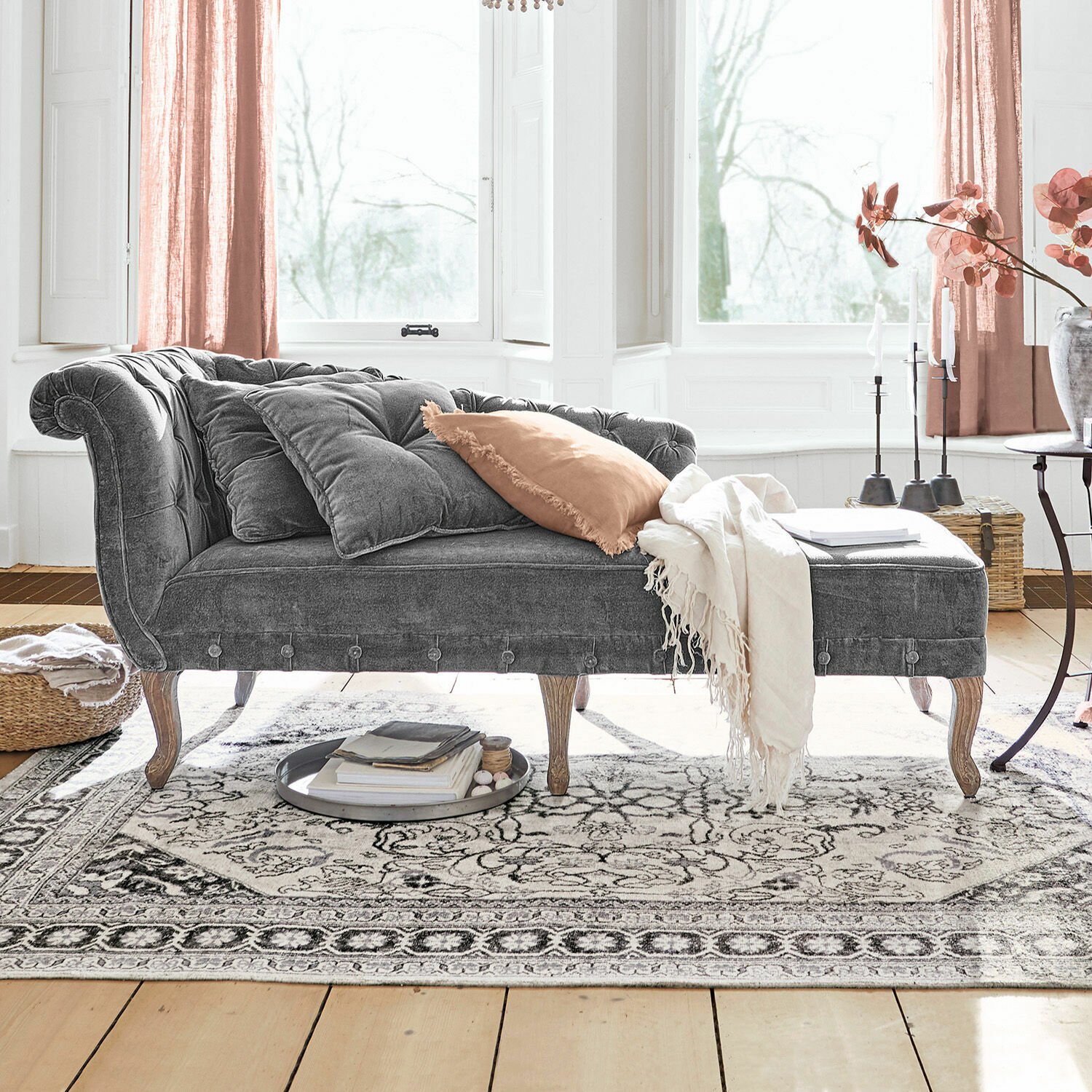 Méridienne Viviani Chaise longue en velours gris avec pieds en bois et coussins clairs dans un salon lumineux