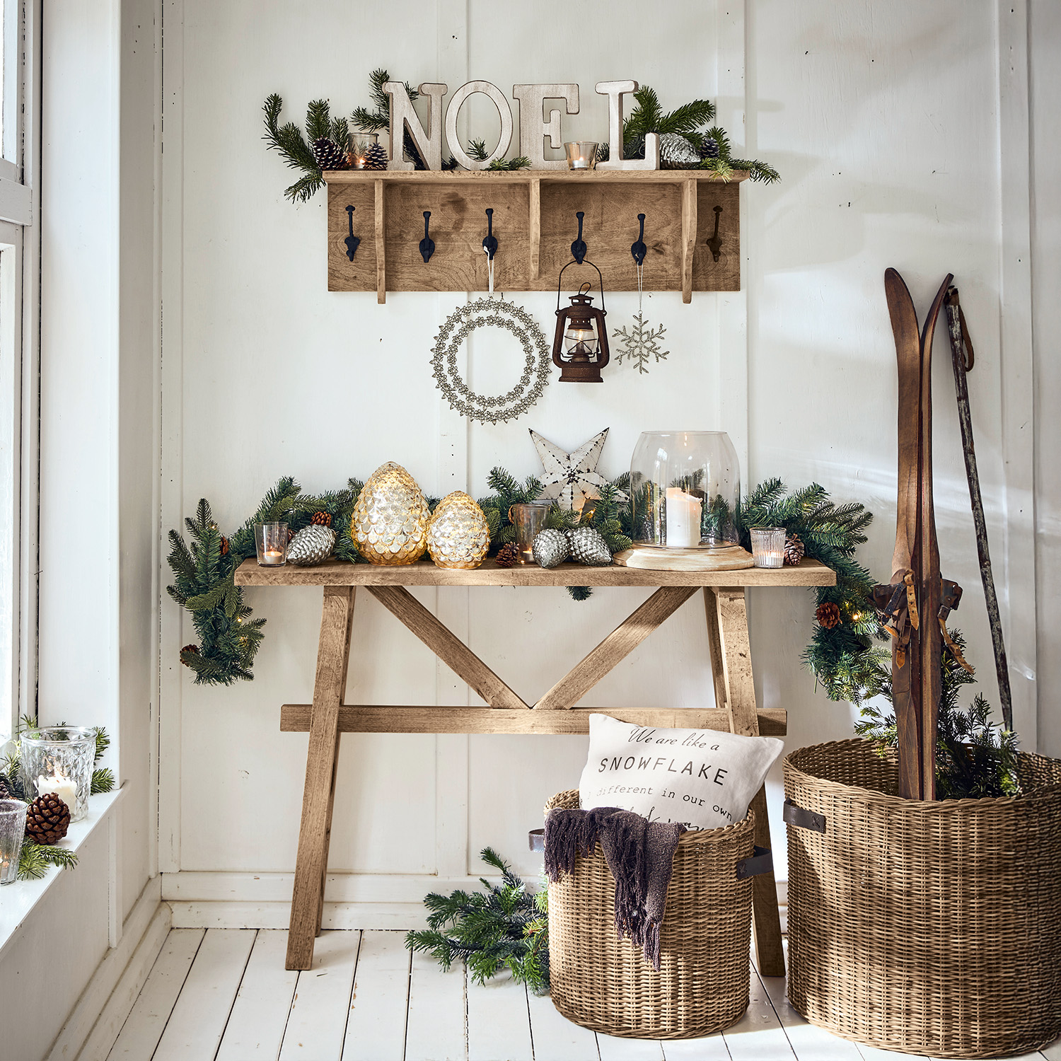 Houten tafel en kapstok met kerstdecoratie, lantaarn en rieten manden met ski's