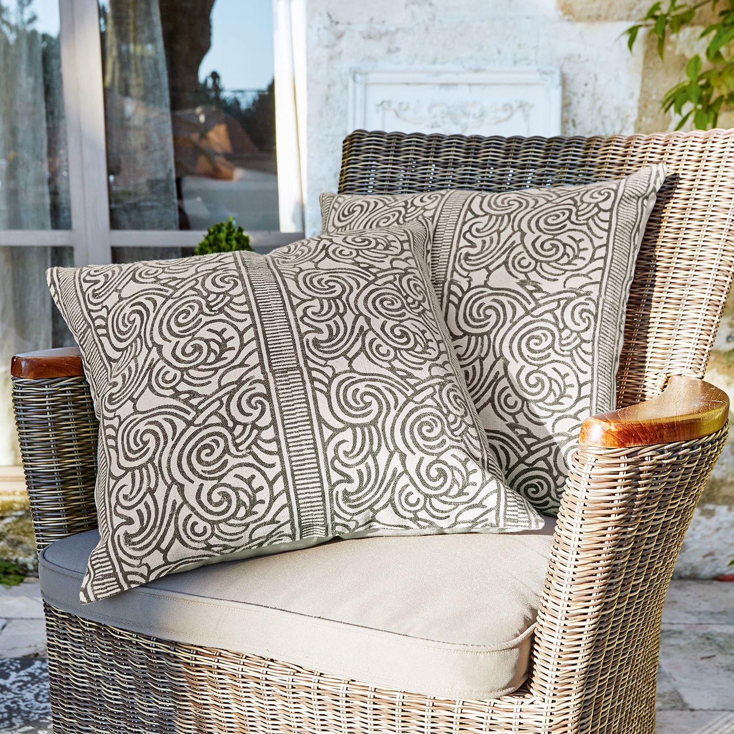 Kussenhoes set van 2 Ensis Twee decoratieve katoenen kussens in beige met bruin patroon op rotan stoel op terras