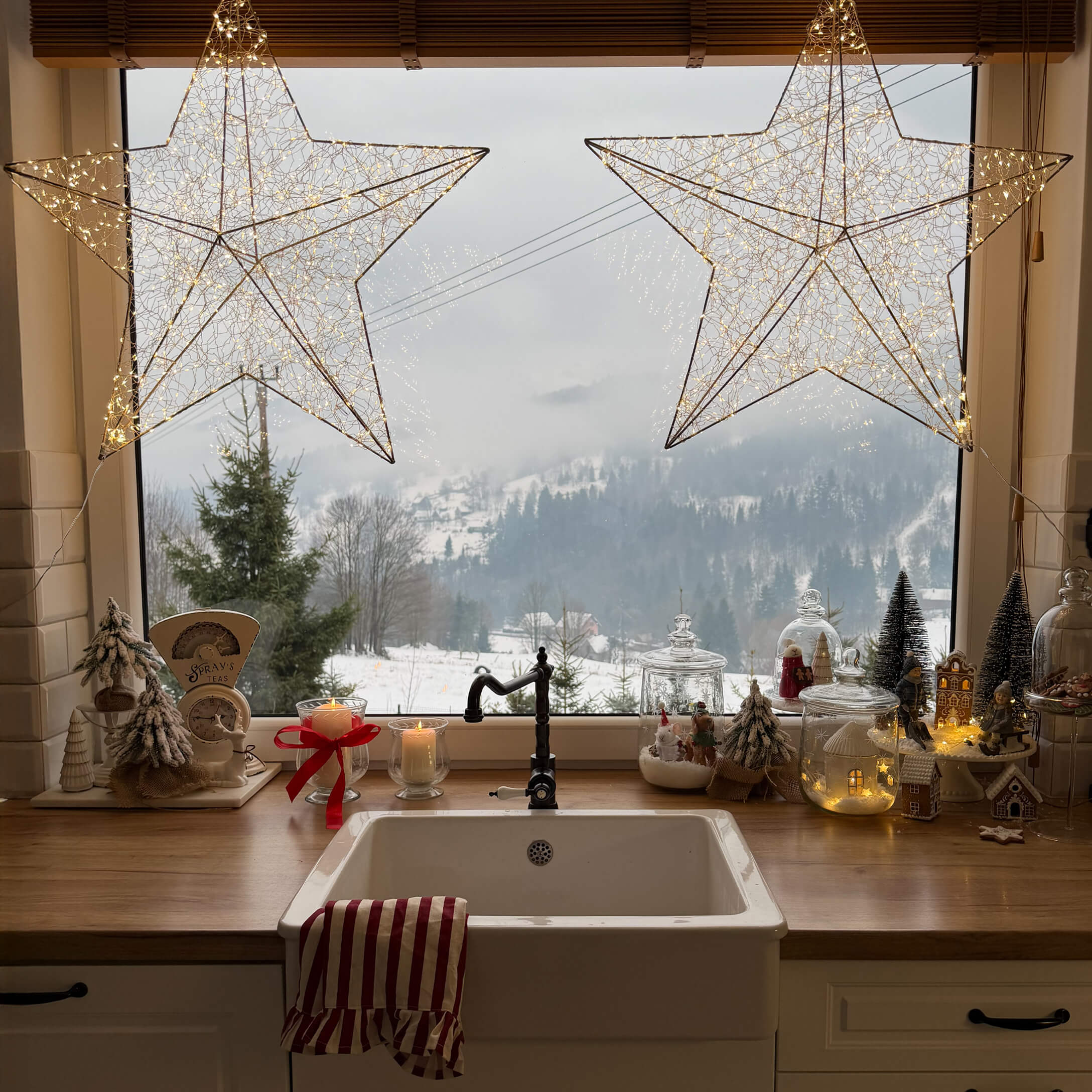Cuisine avec évier blanc, plan de travail en bois, décorations de Noël et vue sur paysage hivernal