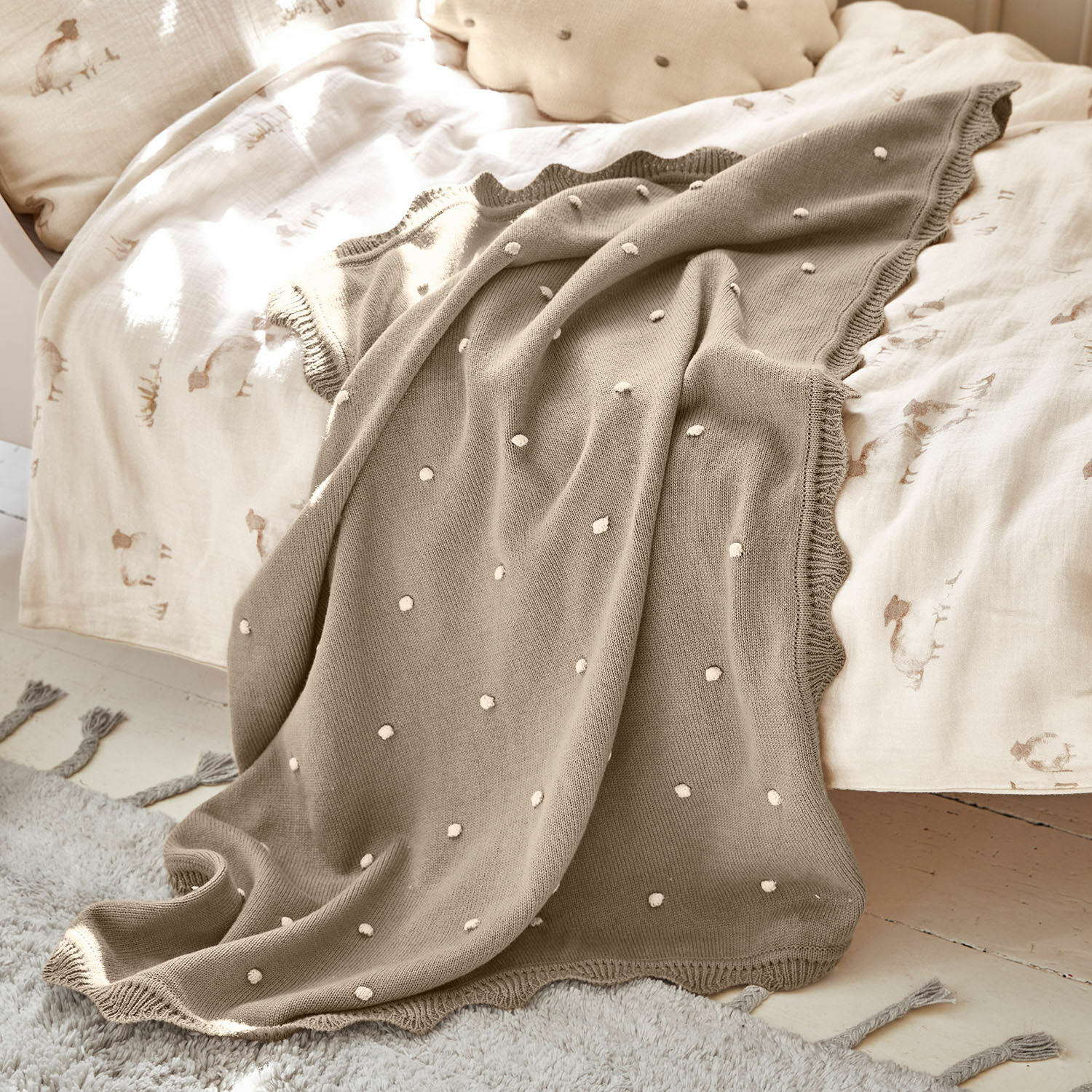Plaid Saphie Beige gebreide deken met witte stippen op licht beddengoed, zachte en decoratieve plaid
