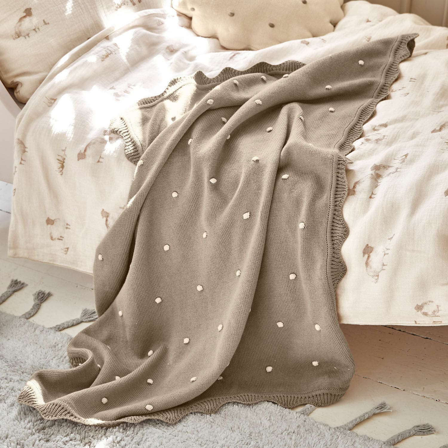 Plaid Saphie Beige gebreide deken met witte stippen op licht beddengoed, zachte en decoratieve plaid