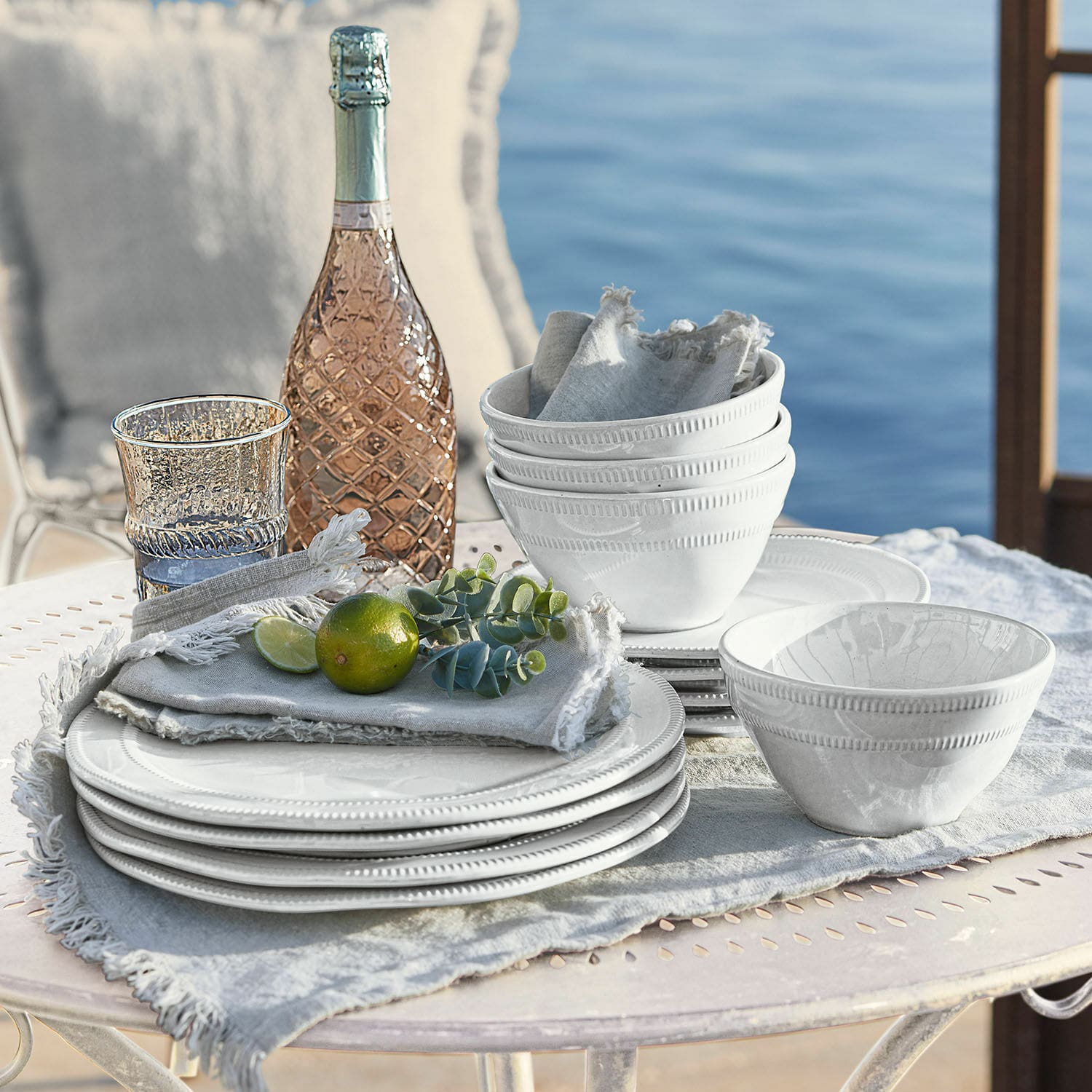 Servies set van 12 Alentejo Witte keramische servies set met borden en kommen op lichte doek bij het water