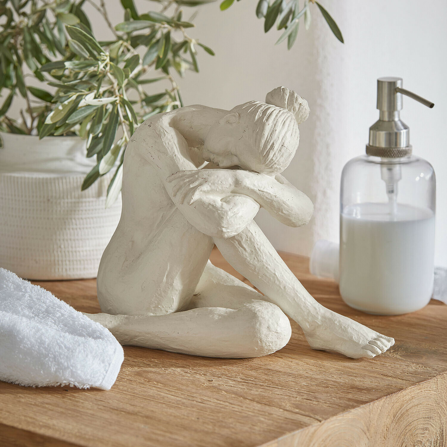 Beeldje Savigné Witte sculptuur van zittende vrouw met hoofd op gebogen knieën op houten blad in badkamer