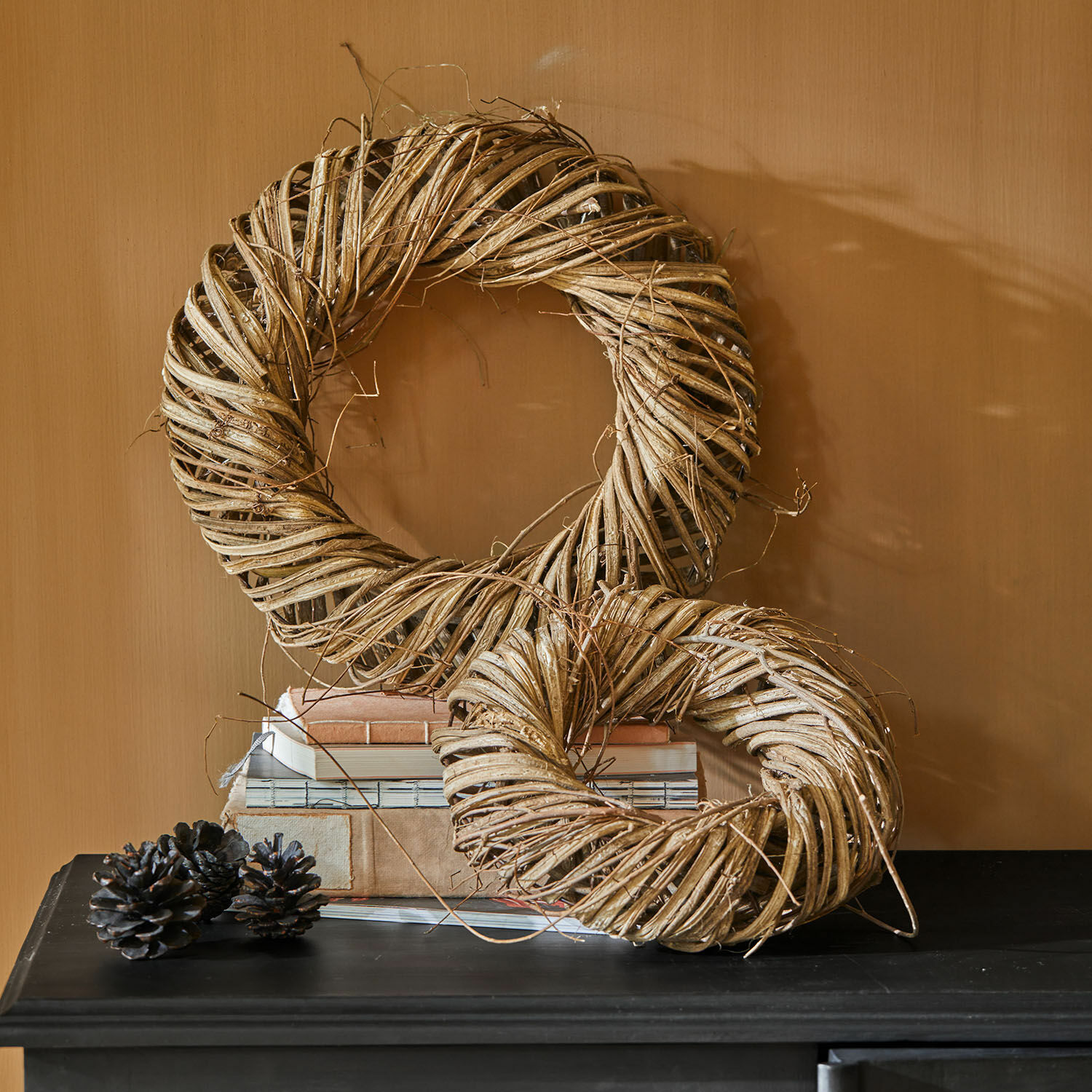 Krans set van 2 Lunéor Decoratieve kransen van natuurlijk beige wilgenmateriaal op een zwarte tafel met boeken