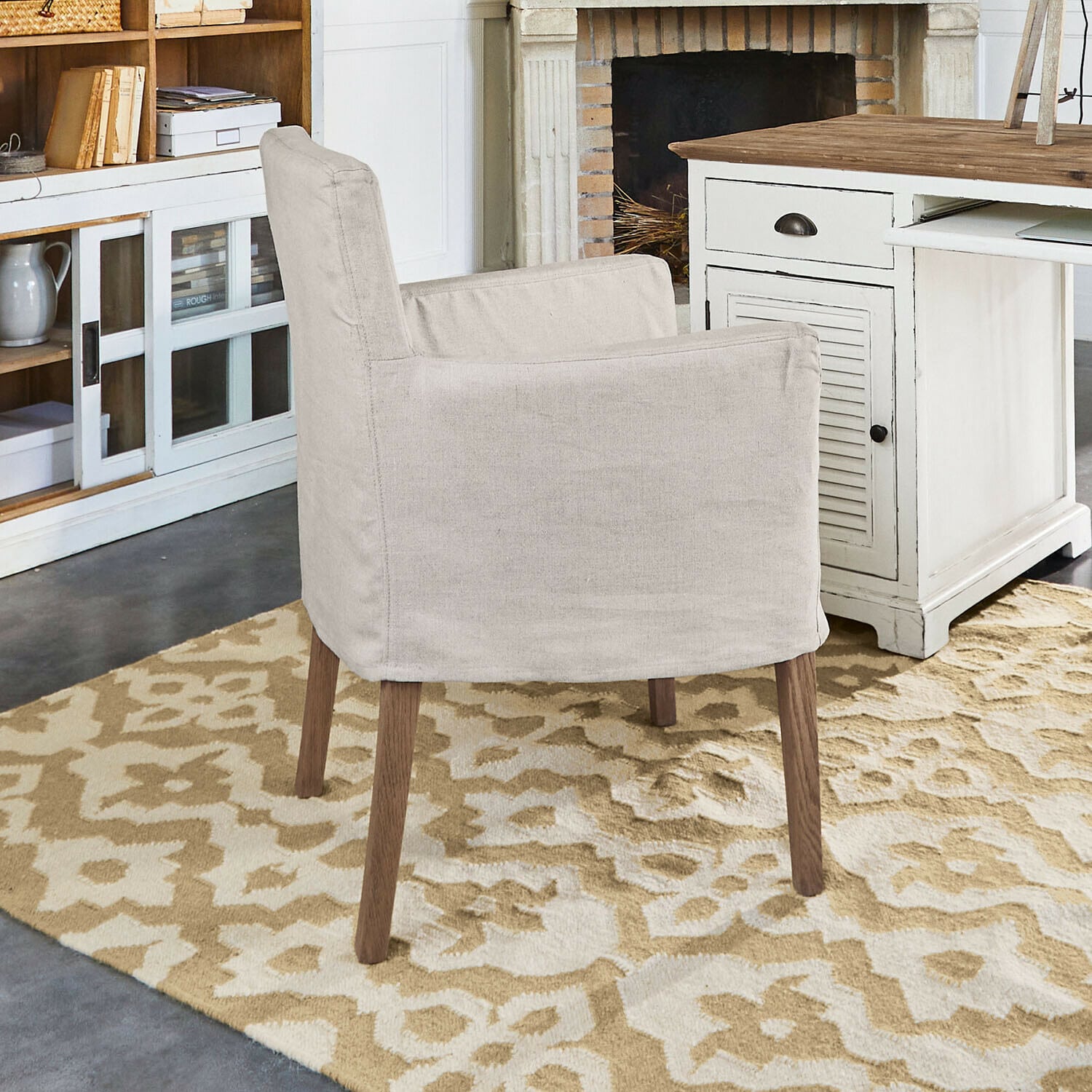 Stoel Longhill Beige stoffen fauteuil met houten poten op patroon vloerkleed in gezellige kamer met open haard