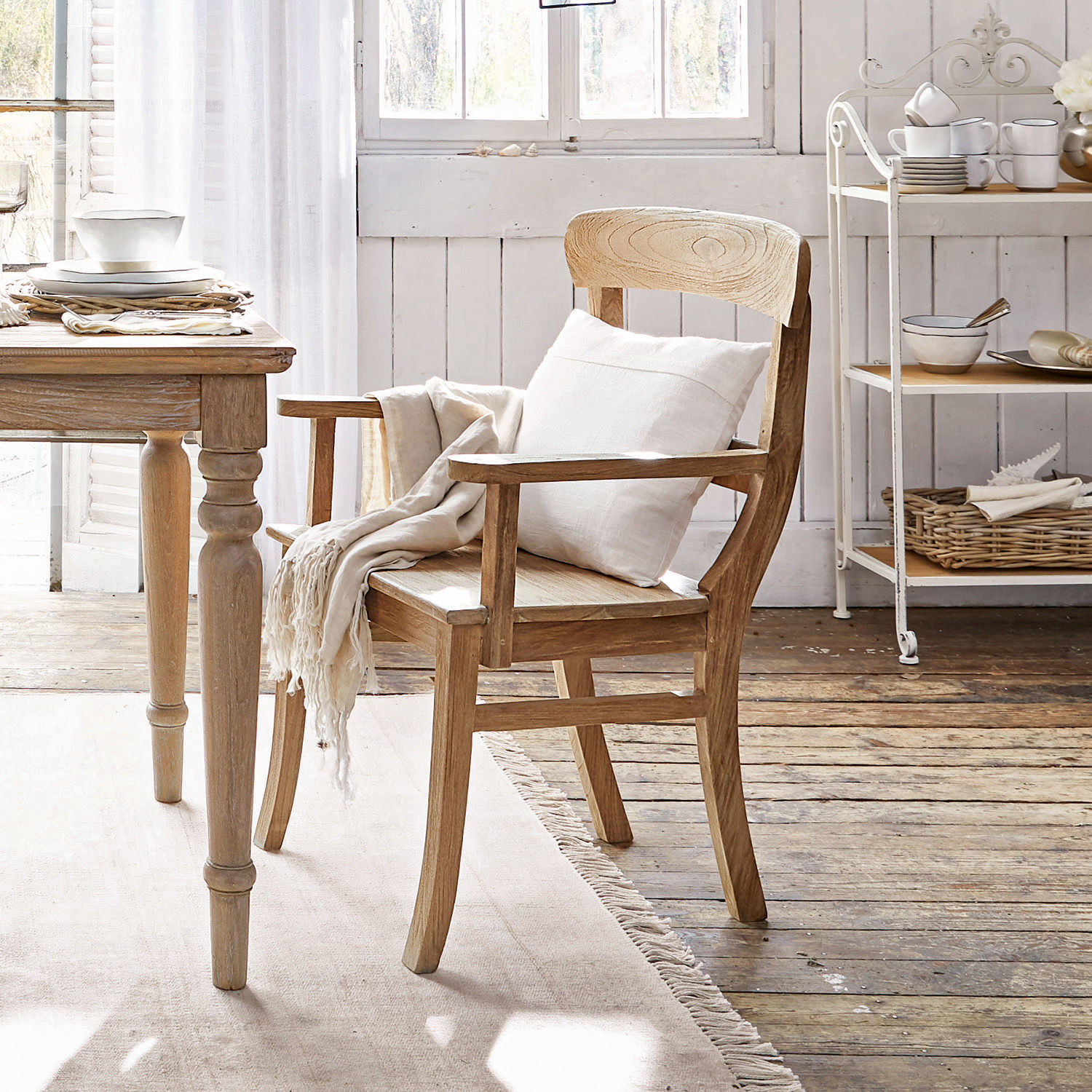 Chaise à accoudoirs Masters Chaise en bois clair avec accoudoirs, coussin blanc et plaid dans un intérieur chaleureux et lumineux