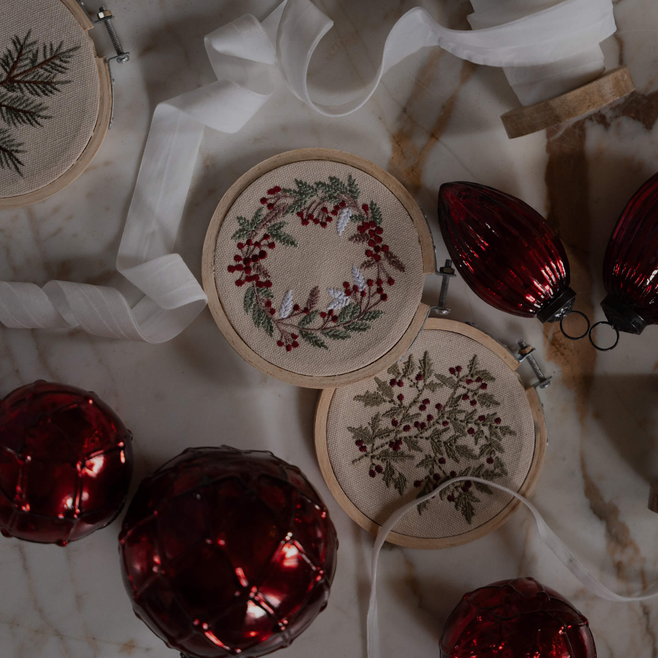 Deux tambours à broder avec motifs de baies rouges et feuilles vertes sur toile beige, décorations de Noël
