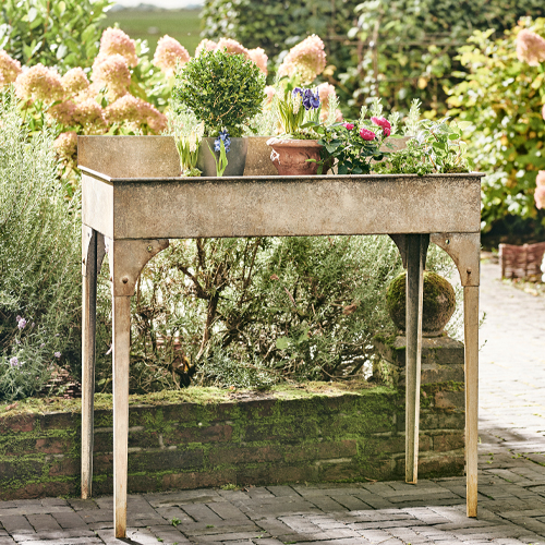 Beige metalen tuintafel met bloemen, ideaal voor het kweken van planten buiten