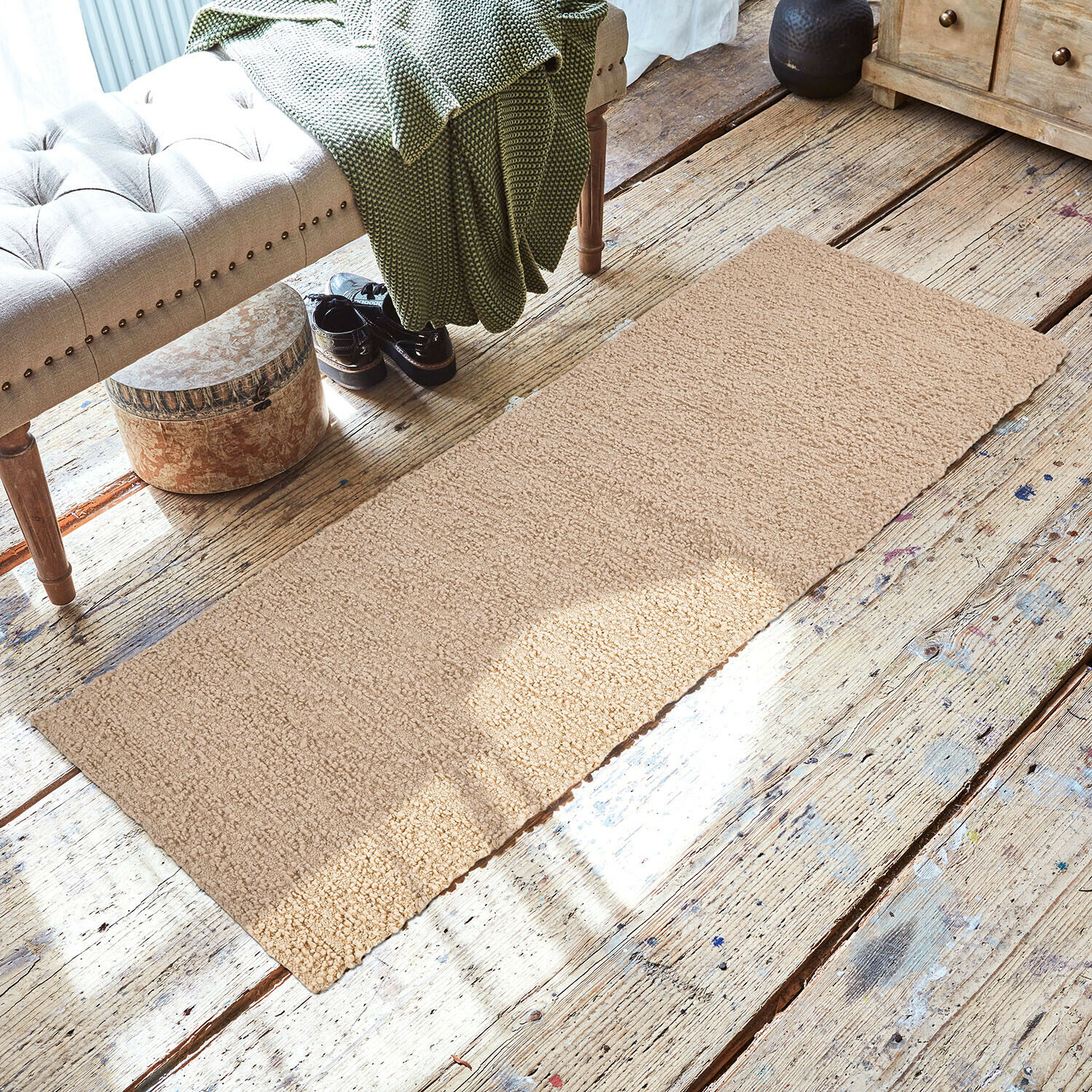 Loper Kaleema Beige vloerkleed van zacht materiaal op houten vloer in gezellige ruimte met bank en groene deken