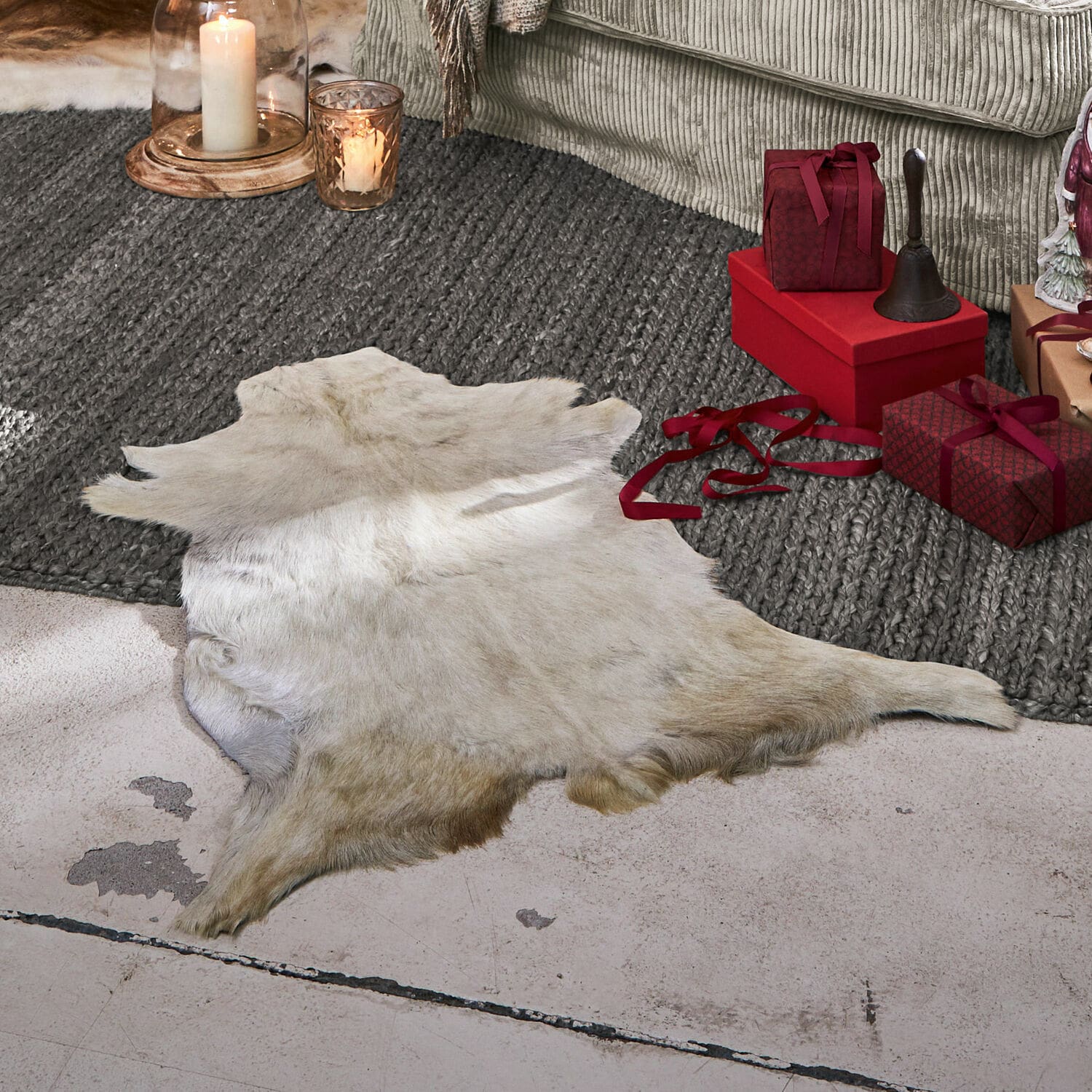 Geitenvacht Piedro Natuurlijke witte dierenhuid op de vloer naast rode cadeaus en kaarsen in de woonkamer