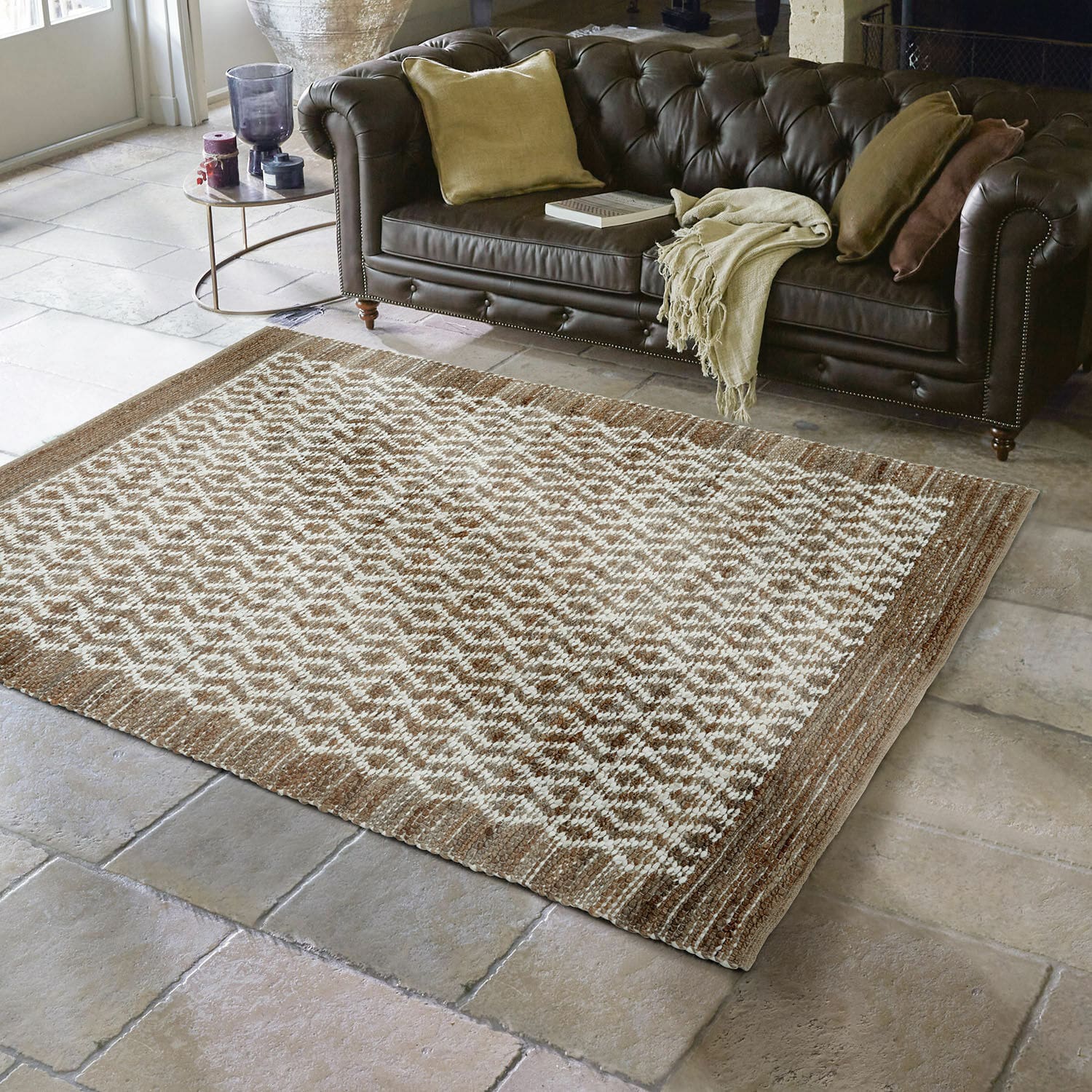 Tapis réversible Amhara Tapis marron et crème à motif géométrique sur sol en pierre devant un canapé en cuir marron foncé